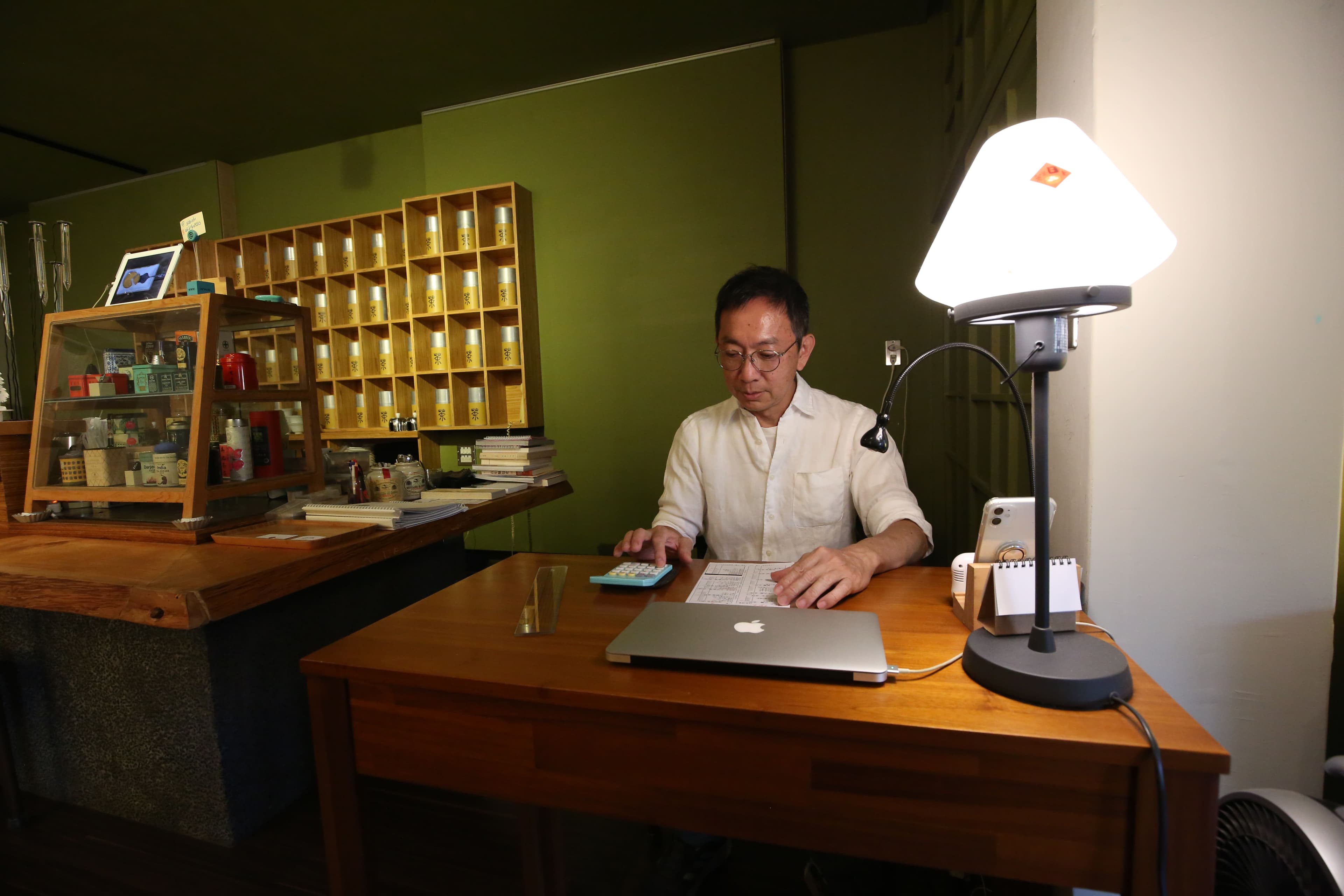 老闆杜宗康坐在自己的小事務桌,後面來自各地的紅茶宛如聯合國。