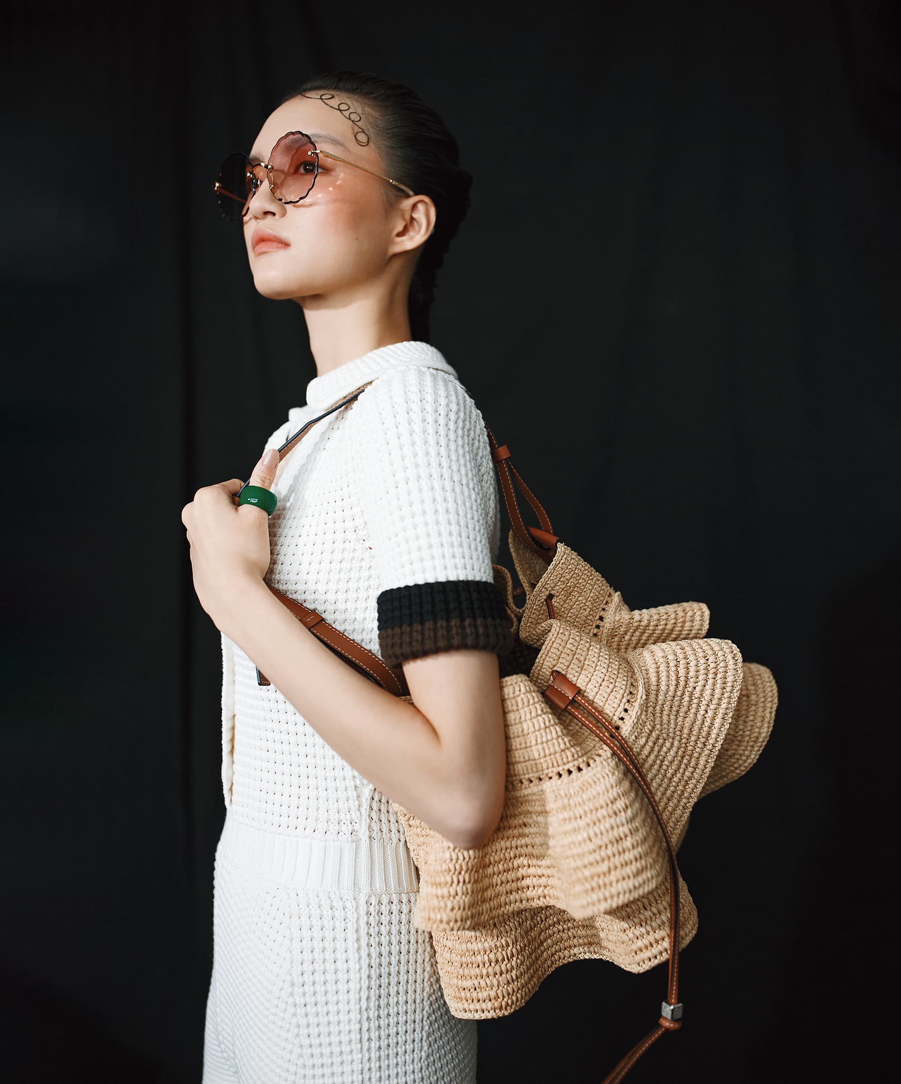 Balloon酒椰葉荷葉邊束口水桶包 NT$50,000 by LOEWE；針織連身短褲 NT$32,900 by FENDI；粉色太陽眼鏡 NT$18,300 by Chloé；草綠色琺琅純銀戒指 NT$29,700 by BOTTEGA VENETA。