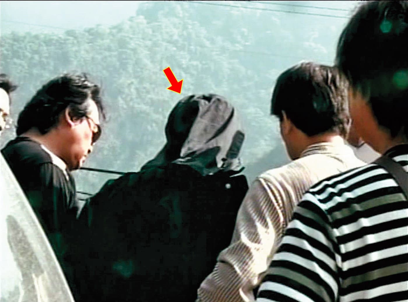  警方押解何男（箭頭者）前往南投丹大林道棄屍山谷，尋找死者遺體。（東森新聞提供）