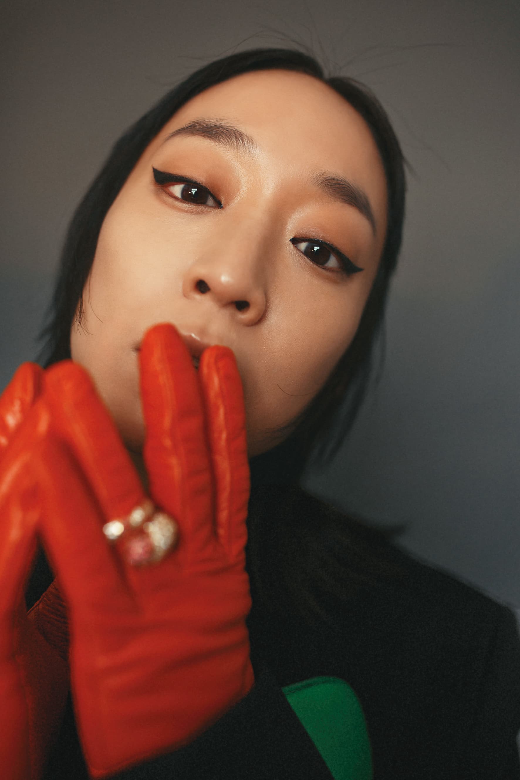黑色單側雙口袋羊毛外套 NT$96,500 by BOTTEGA VENETA；鸚鵡綠螺旋繞身皮帶 NT$81,700 by BOTTEGA VENETA；紫紅白鋯石純銀鍍金戒指 NT$51,300 by BOTTEGA VENETA；橘色口袋皮革手套 NT$34,000 by PRADA。