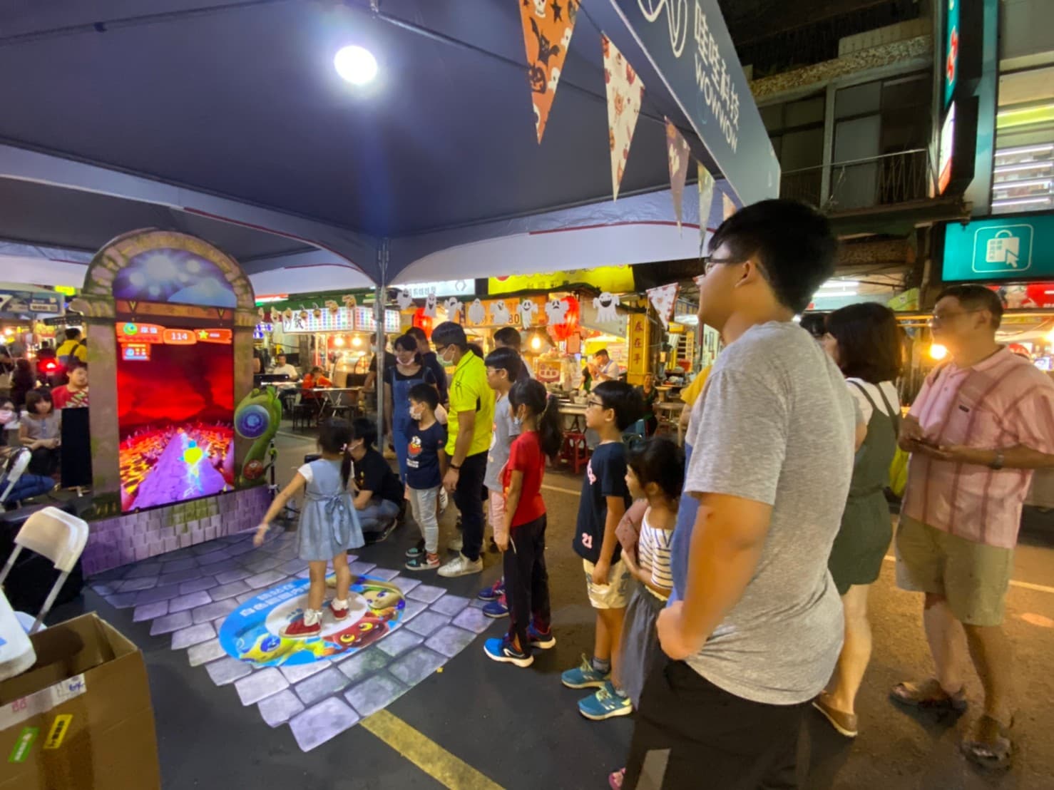 哇哇去年將《妖果小學堂》大型機台在高雄六合夜市展出,大批逛街民眾駐足觀看試玩。(翻攝自哇哇科技FB)