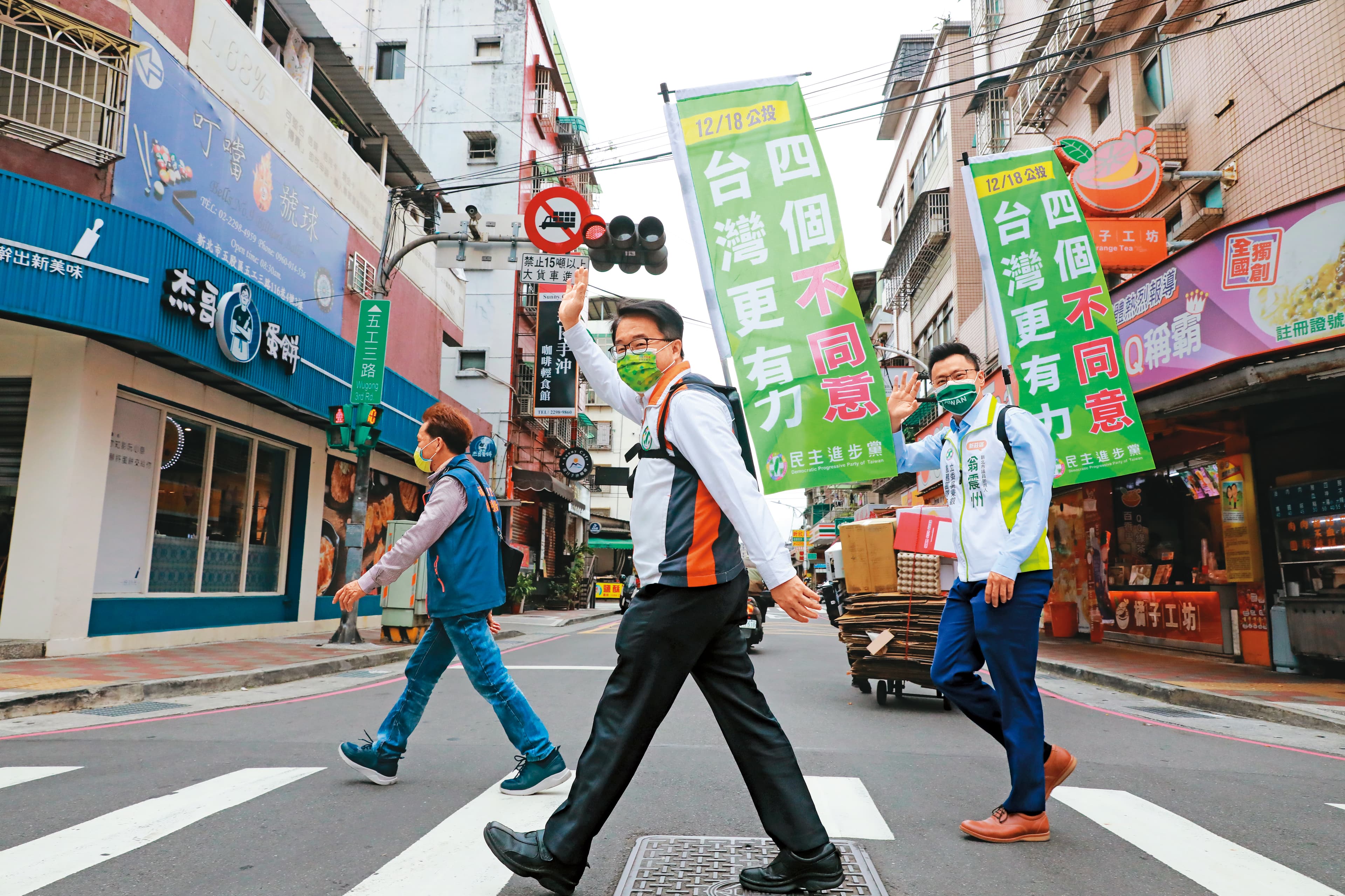 民進黨許多公職祭奇招宣傳公投,新北綠委吳秉叡(中)就率子弟兵翁震州(右)背工字旗徒步掃街。
