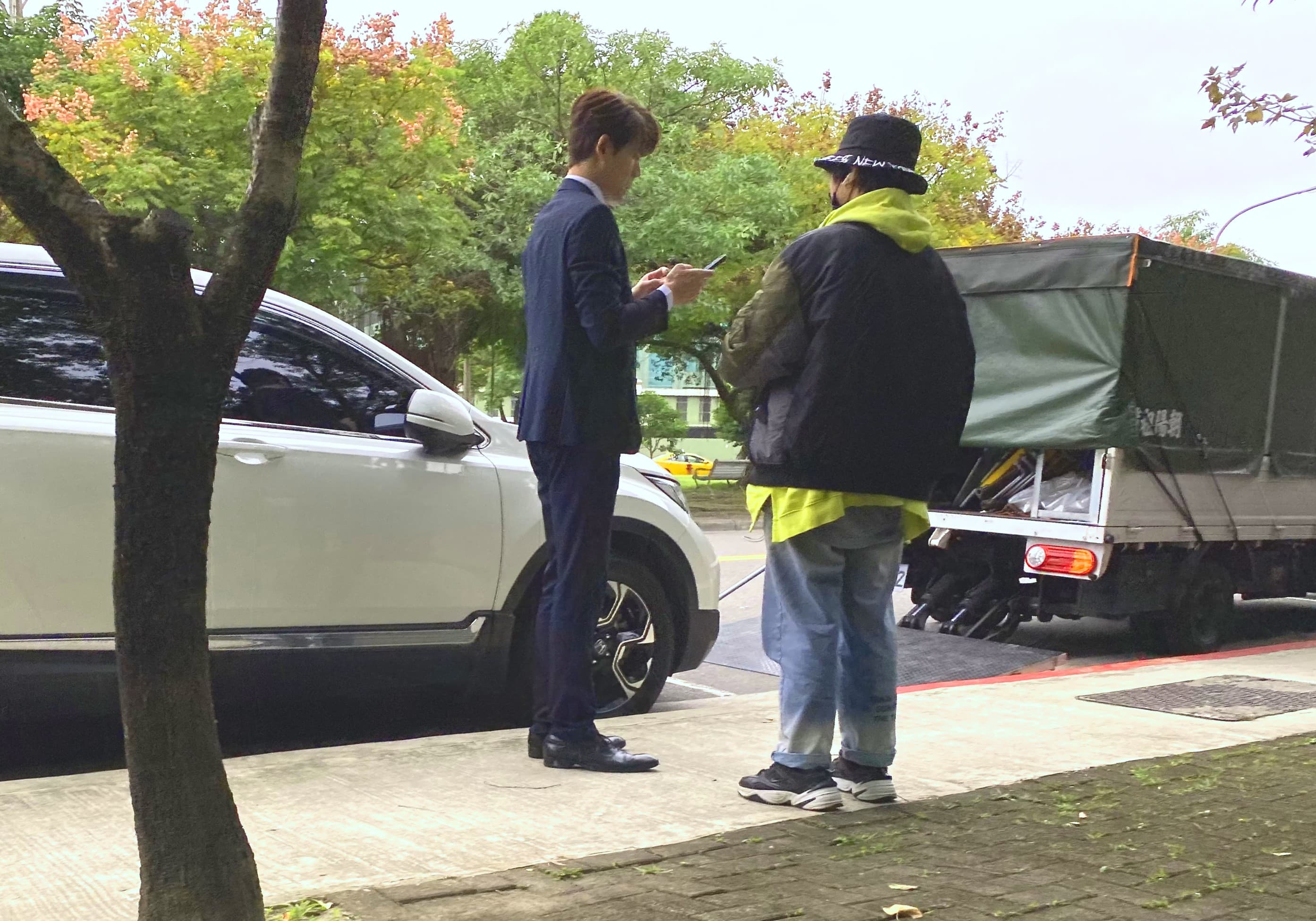 余秉諺日前在台北市內湖路邊拍三立八點檔《天之驕女》,利用空檔在一旁忙碌滑手機。(讀者提供)
