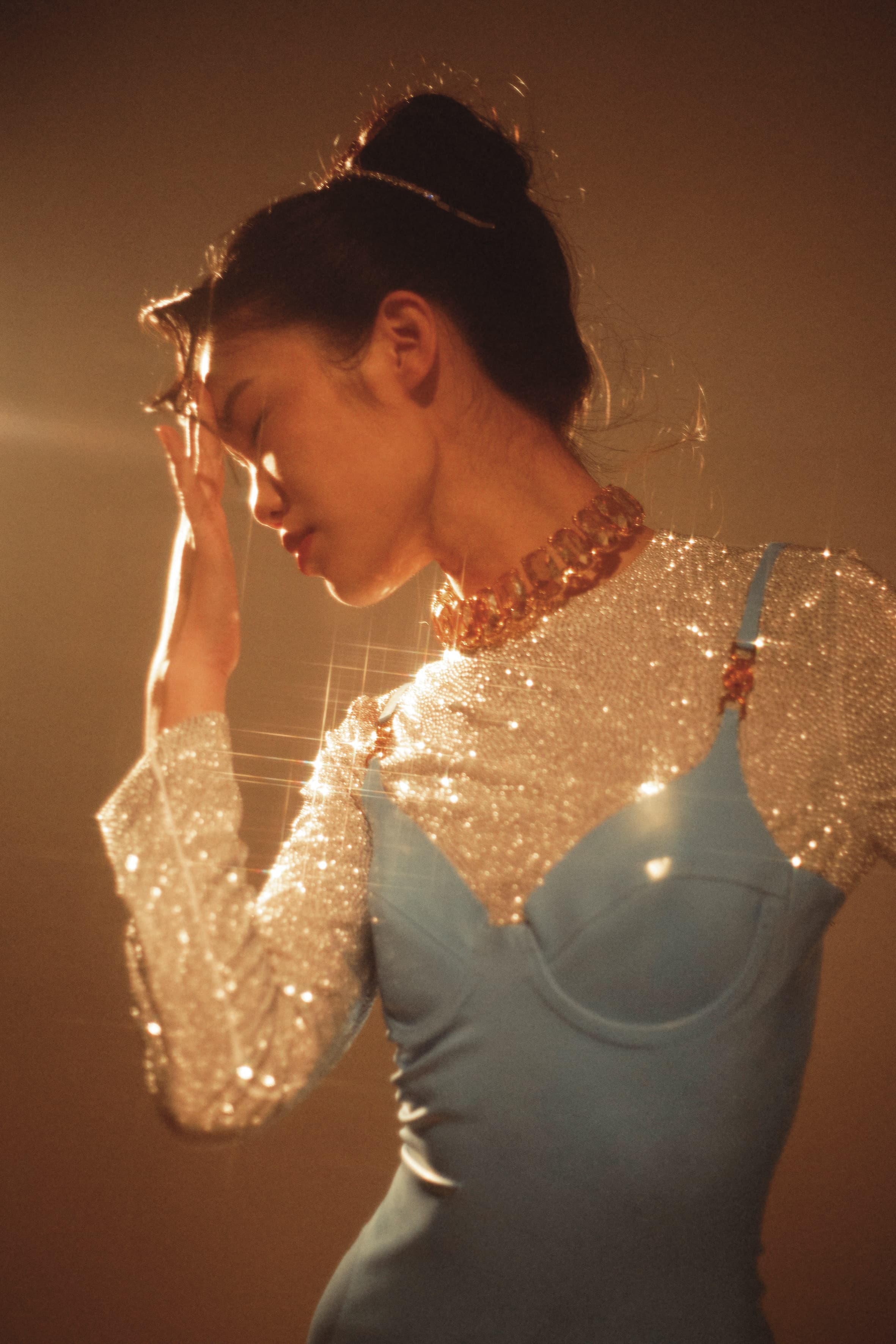 水藍色細肩乳膠洋裝 NT$74,500 by VERSACE；水晶墜飾短版上衣 NT$105,000 by MIU MIU；水晶綴飾頭箍 價格店洽 by MIU MIU；Harmonia水晶項鍊 NT$32,900 by SWAROVSKI。