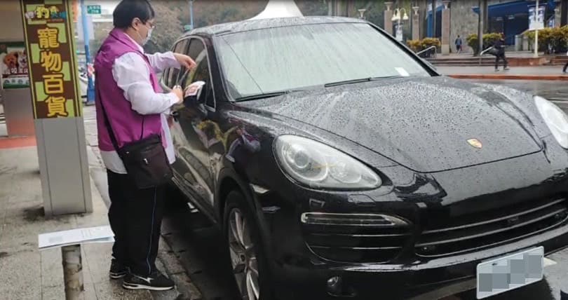 新北分署執行人員在新莊區路邊收費停車格冒雨張貼封條，查封許姓男子的保時捷。（翻攝畫面）