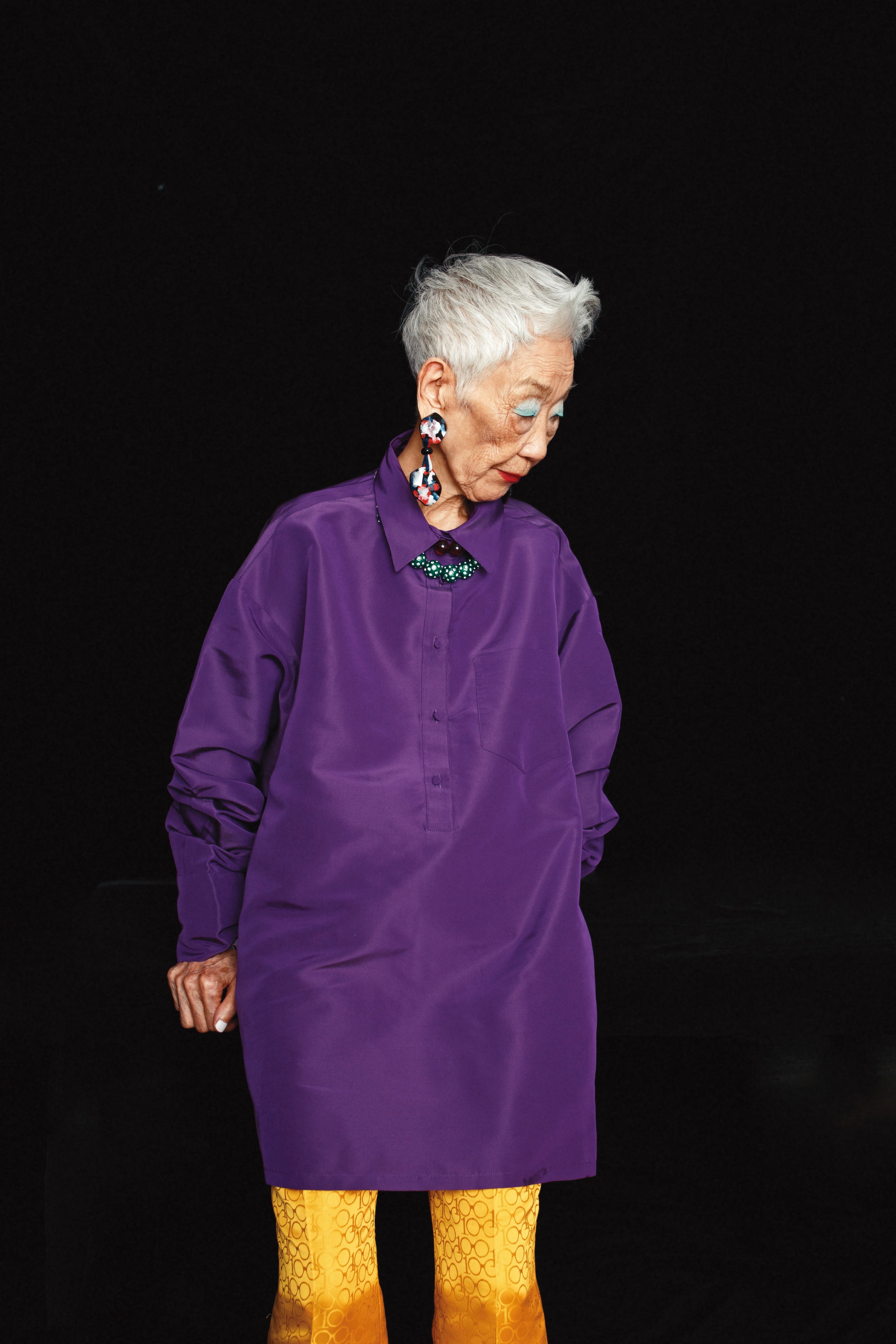 紫色寬版襯衫，價格店洽，by VALENTINO；黃色緹花長褲，NT$2,999，by Iris Apfel X H&M；不規則印花耳環，價格店洽，by Giorgio Armani；雙色珠珠項鍊，NT$1,999，by Iris Apfel X H&M。