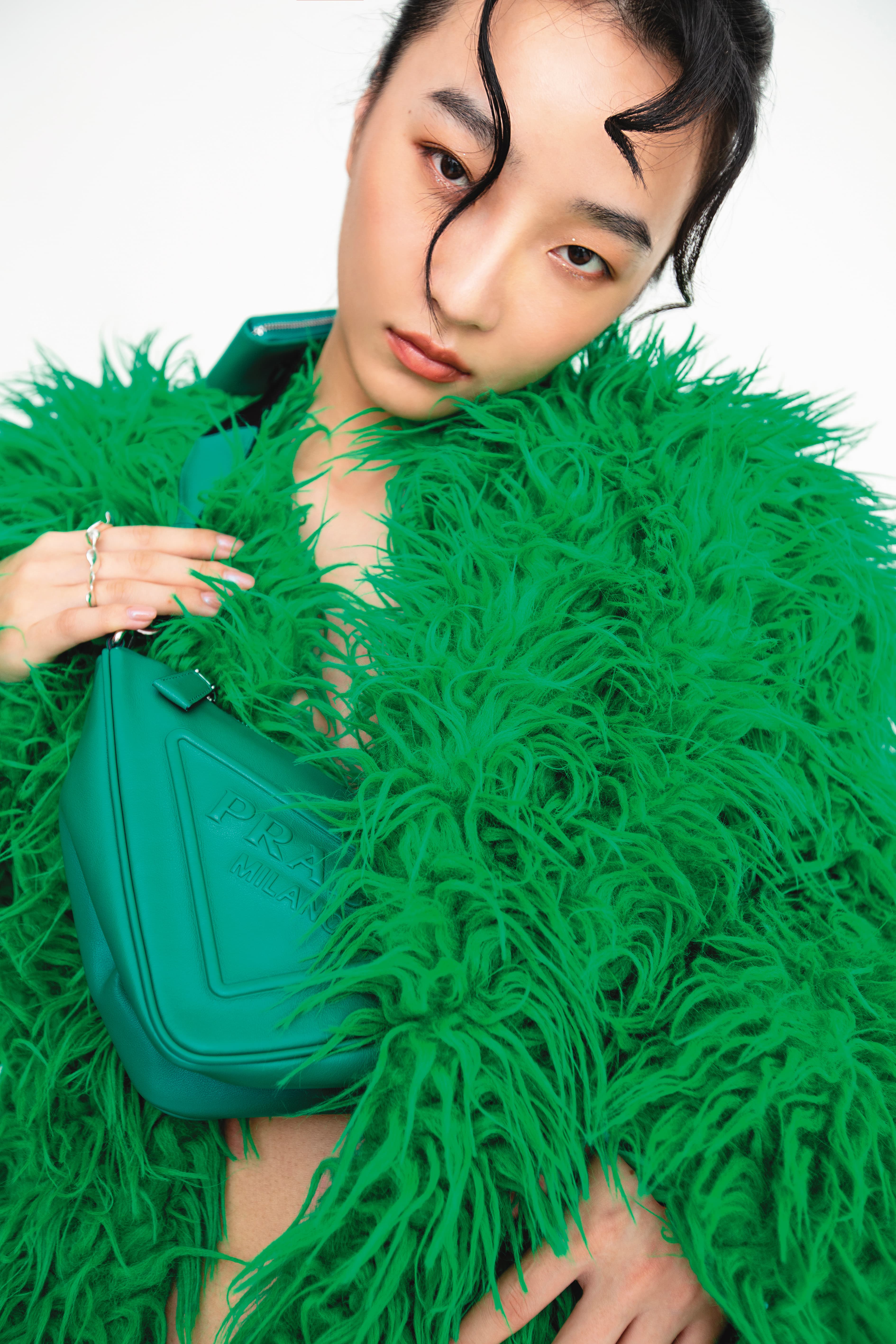 Triangle肩背包 NT$68,000 by PRADA；綠色短版仿皮草外套 NT$3,499 by Iris Apfel X H&M；三指銀戒 NT$5,280 by OLIVIA YAO JEWELLERY
