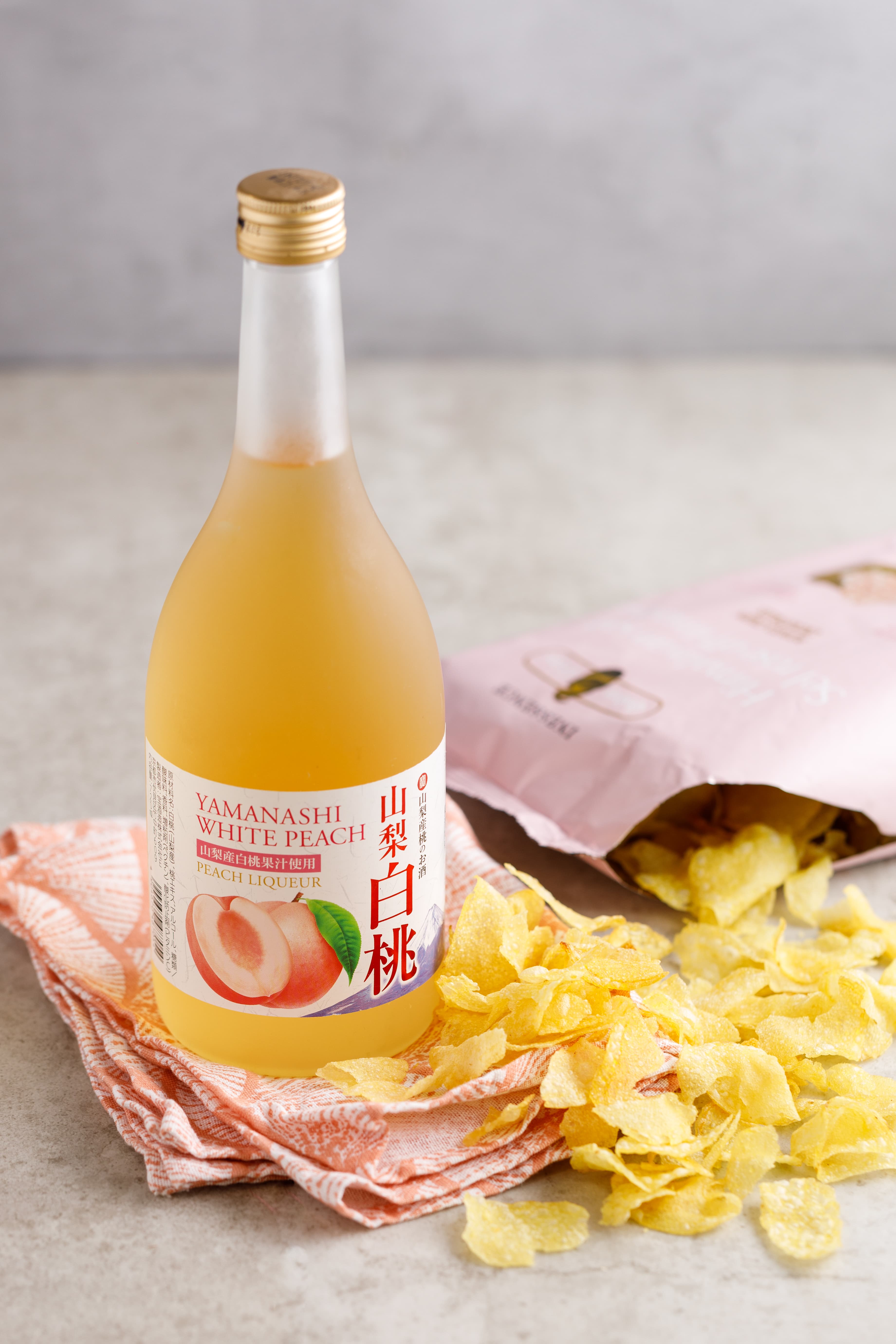 「喜馬拉雅粉紅岩鹽風味洋芋片」(右,119元/包)樸真的鹽味,反而襯托「寶酒造 山梨白桃利口酒」(左,750元/瓶)的甜。