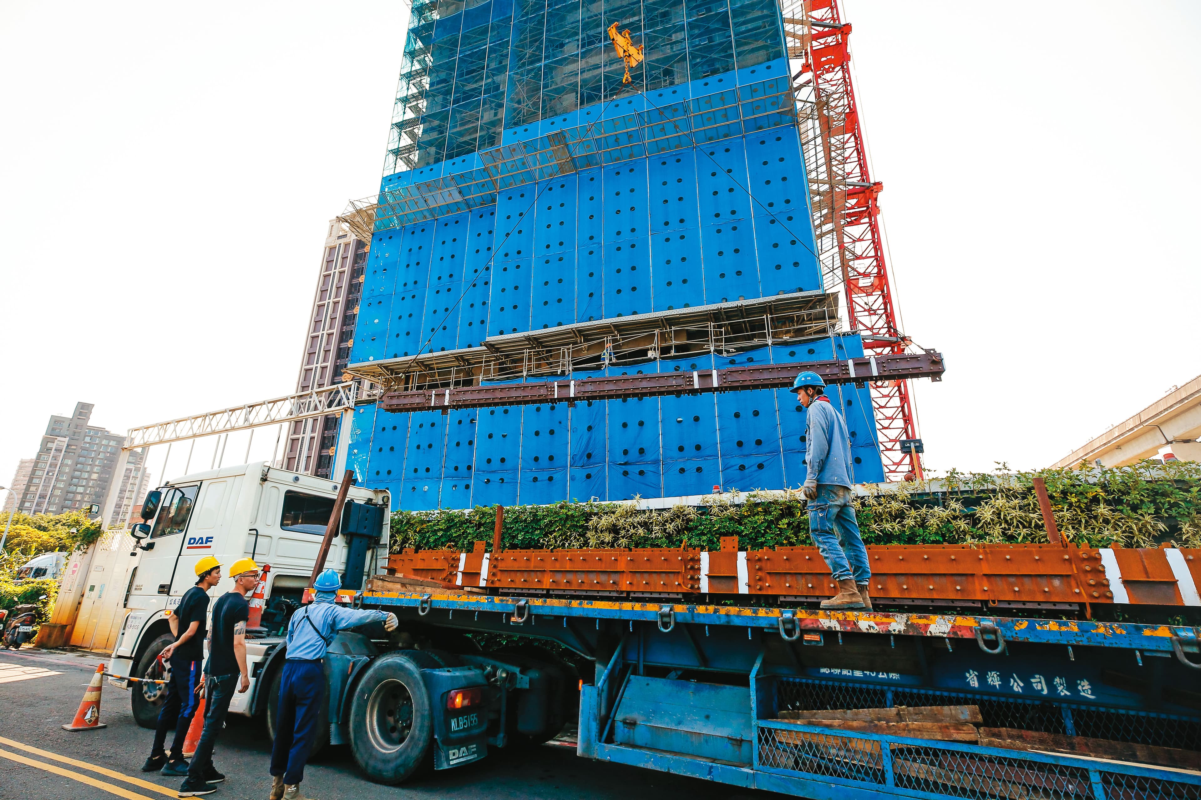 興建台北雙子星相當於蓋1.5座台北101,屆時鋼骨需求可想而知。圖為大型貨車載運鋼骨至某大樓工地。(資料照片)