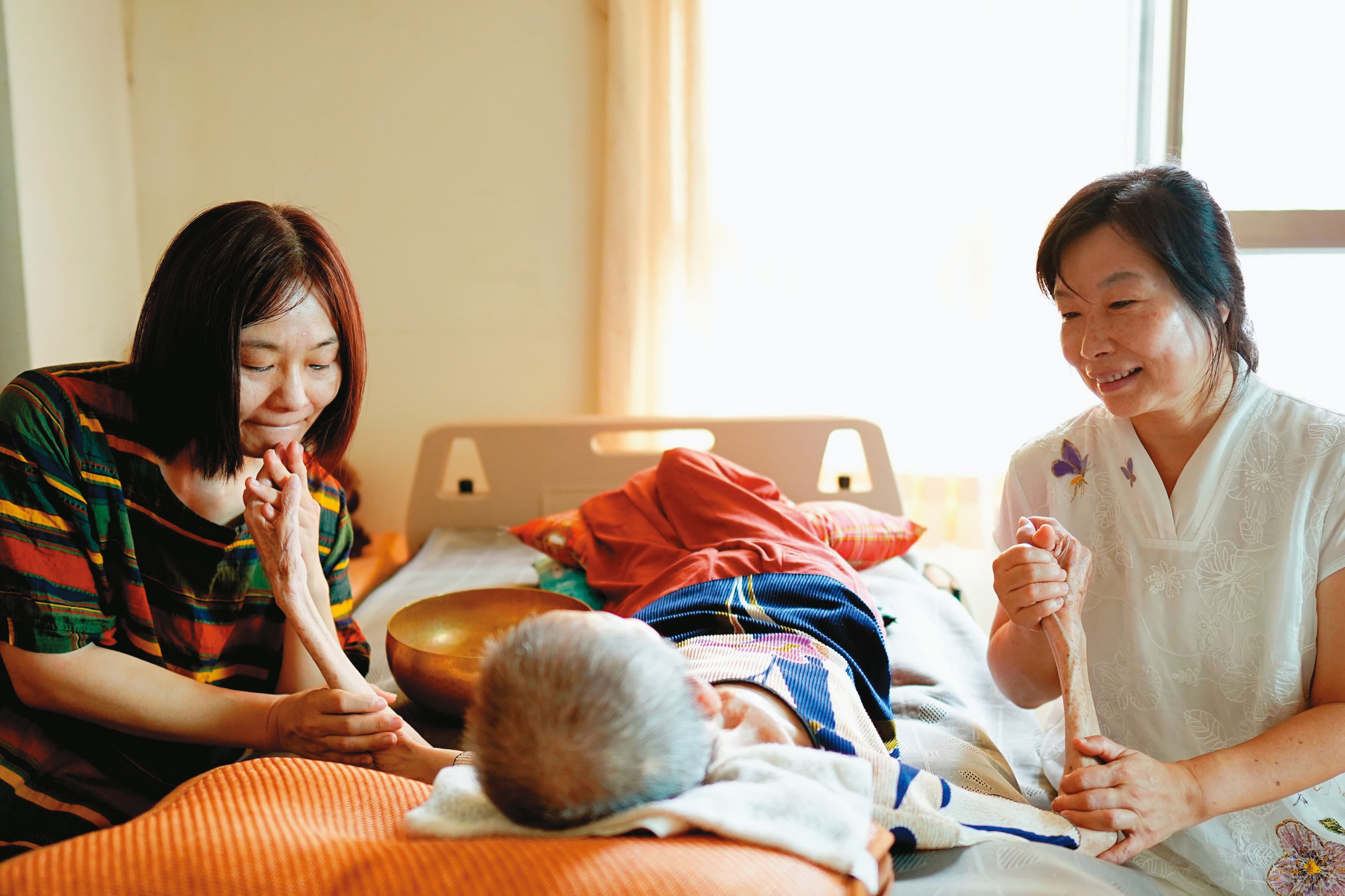 臥床4年,盈晰(右)母親瘦到僅剩28公斤。盈晰姊妹倆心疼母親受苦,不斷跟她說話、祝禱,試圖減輕她的疼痛,安頓她的身心。(林韋言攝)