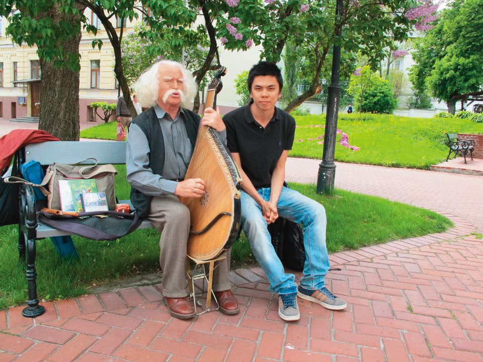 老爺爺史提潘(左)是徐裕軒(右)在烏克蘭的第一個好友,2人相識至今12年,仍然保有聯絡。圖為徐裕軒赴烏克蘭交換時,與彈奏班杜拉琴的史提潘合影。(徐裕軒提供)