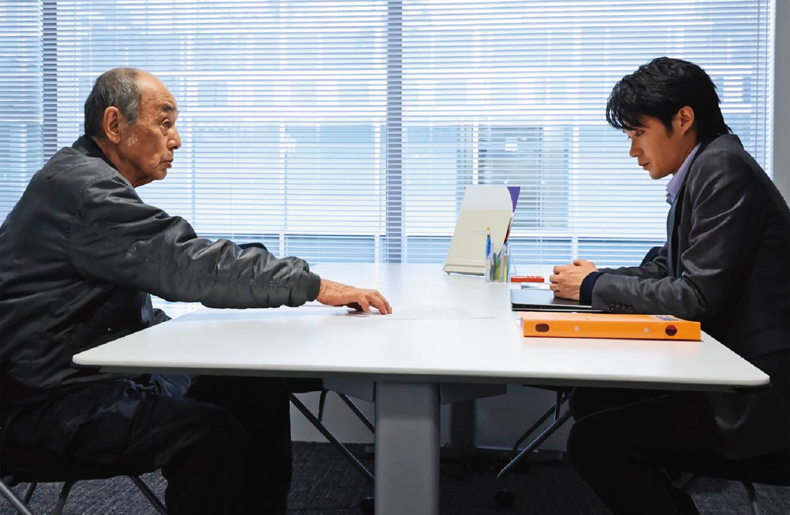 磯村勇斗(右)在《七五計劃》飾演承辦「七五計劃」的公務人員,卻因遇上親戚申請而有了遲疑。(天馬行空提供)