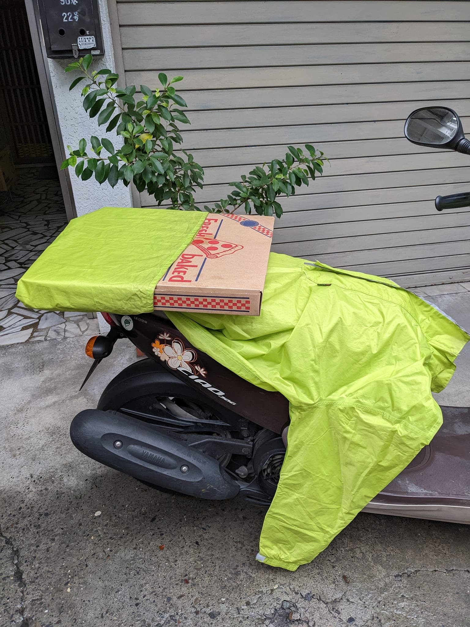 有網友分享如何用一件雨衣將整盒大披薩綁在機車後座。(翻攝自Costco好市多 商品經驗老實說)
