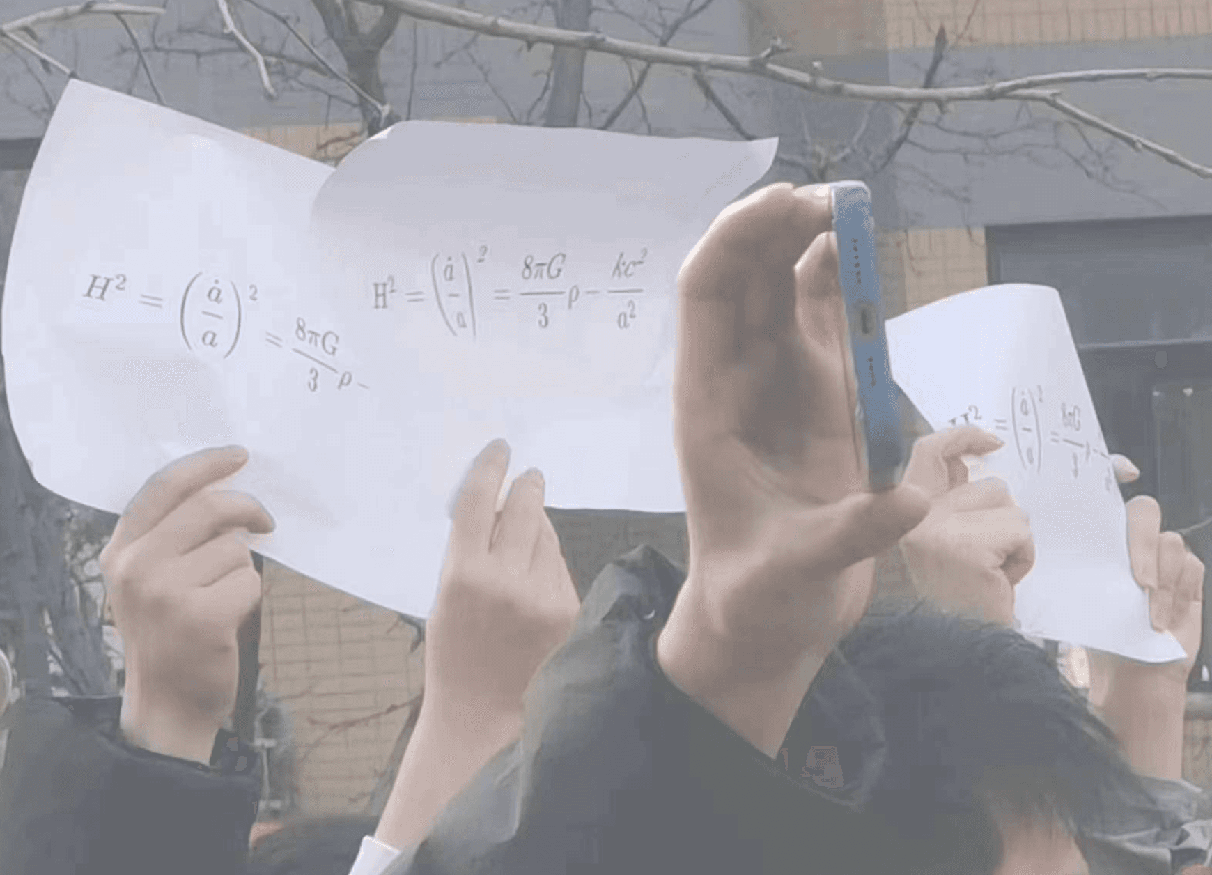 新疆烏魯木齊惡火釀10死,使各地不滿情緒暴漲,其中北京清華大學學生舉著寫有方程式的白色A4紙,背後藏抗議訴求。(翻攝羅冠聰推特)