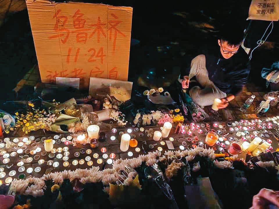 上海烏魯木齊中路現場點起蠟燭、擺放白色菊花,願烏魯木齊火災逝者安息。(翻攝網路)