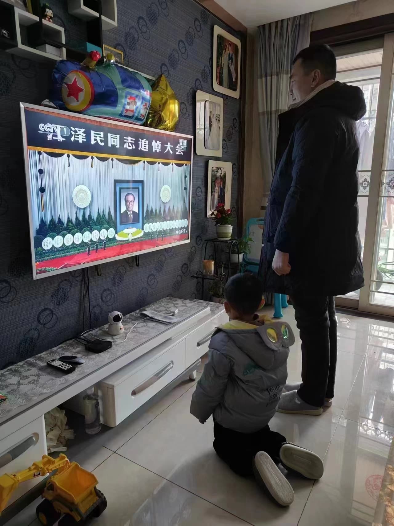 有家長和小孩在看江澤民追悼會時,要小孩下跪,引起議論。(翻攝自推特)