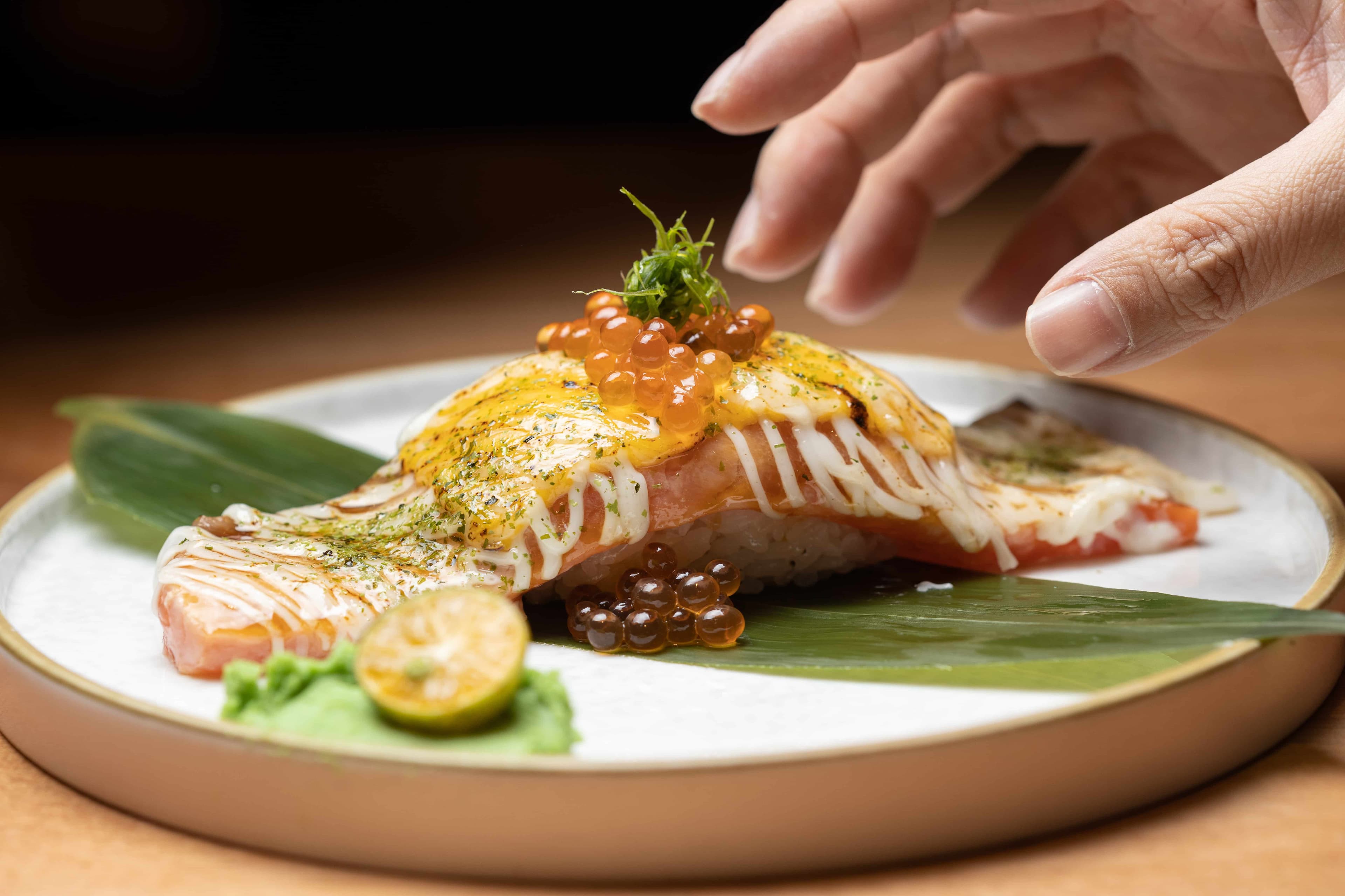 「巨型起司鮭魚握」一貫可以抵三貫!一旁的金桔搭配山葵,解膩又爽口。(198元/貫)