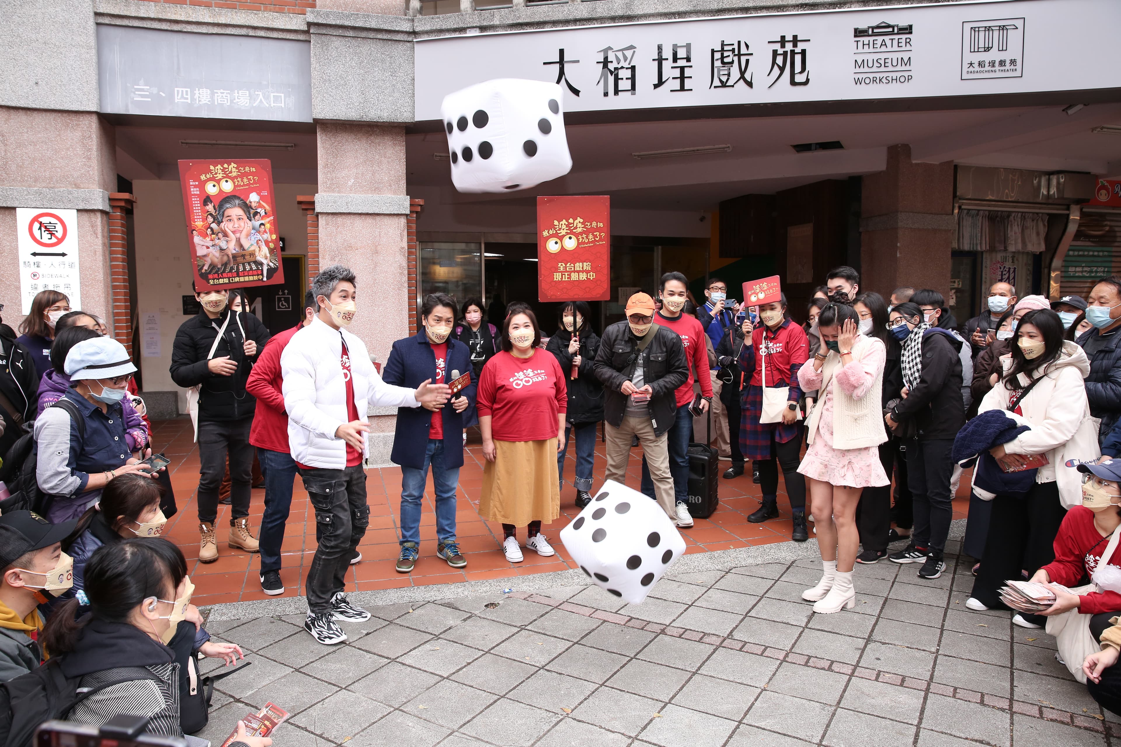 眾人在廣場與遊客玩擲骰子遊戲,一群人玩得十分開心。