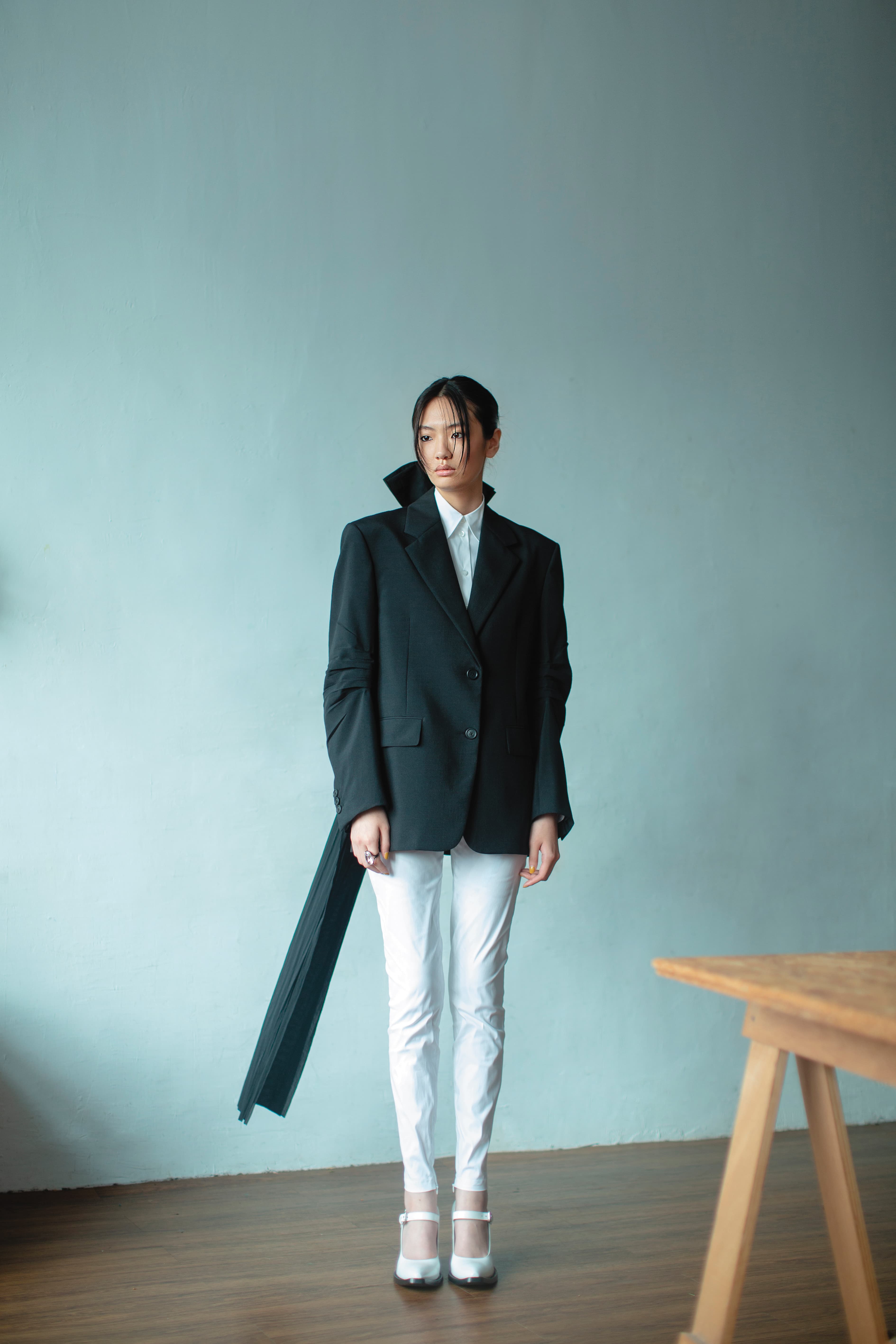 黑色西裝外套 價格店洽 by PRADA／白色襯衫 價格店洽 by PRADA／白色長褲 價格店洽 by PRADA／白色繫帶瑪莉珍高跟鞋 價格店洽 by PRADA／Harmonia戒指 NT$8,000 by SWAROVSKI
