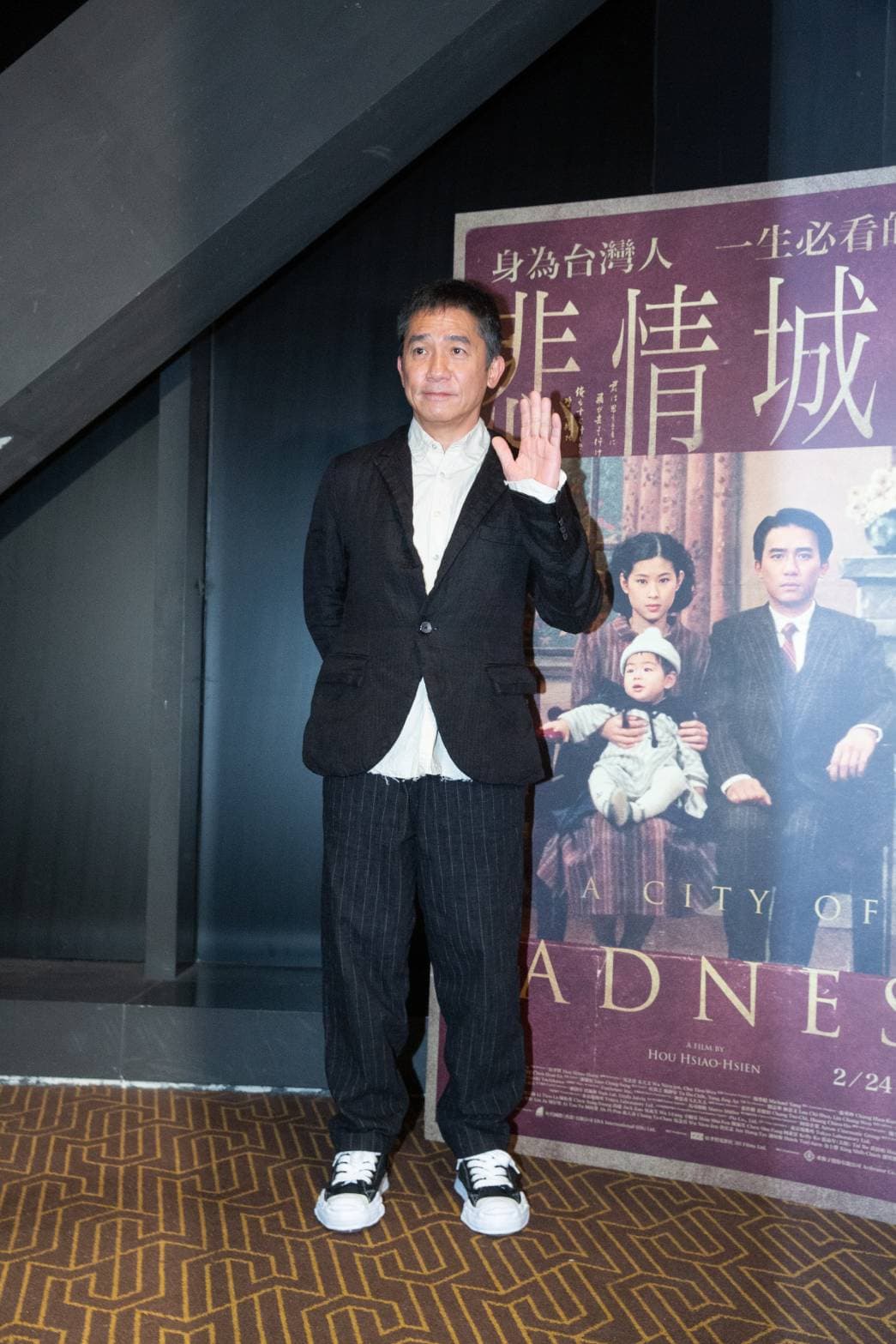 梁朝偉身穿白襯衫黑西裝,搭配條紋褲與帆布鞋,打扮簡單中也帶著時尚。