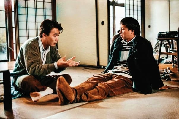導演侯孝賢(右)與27歲的梁朝偉(左)在電影拍攝現場輕鬆聊天討論。(牽猴子提供)