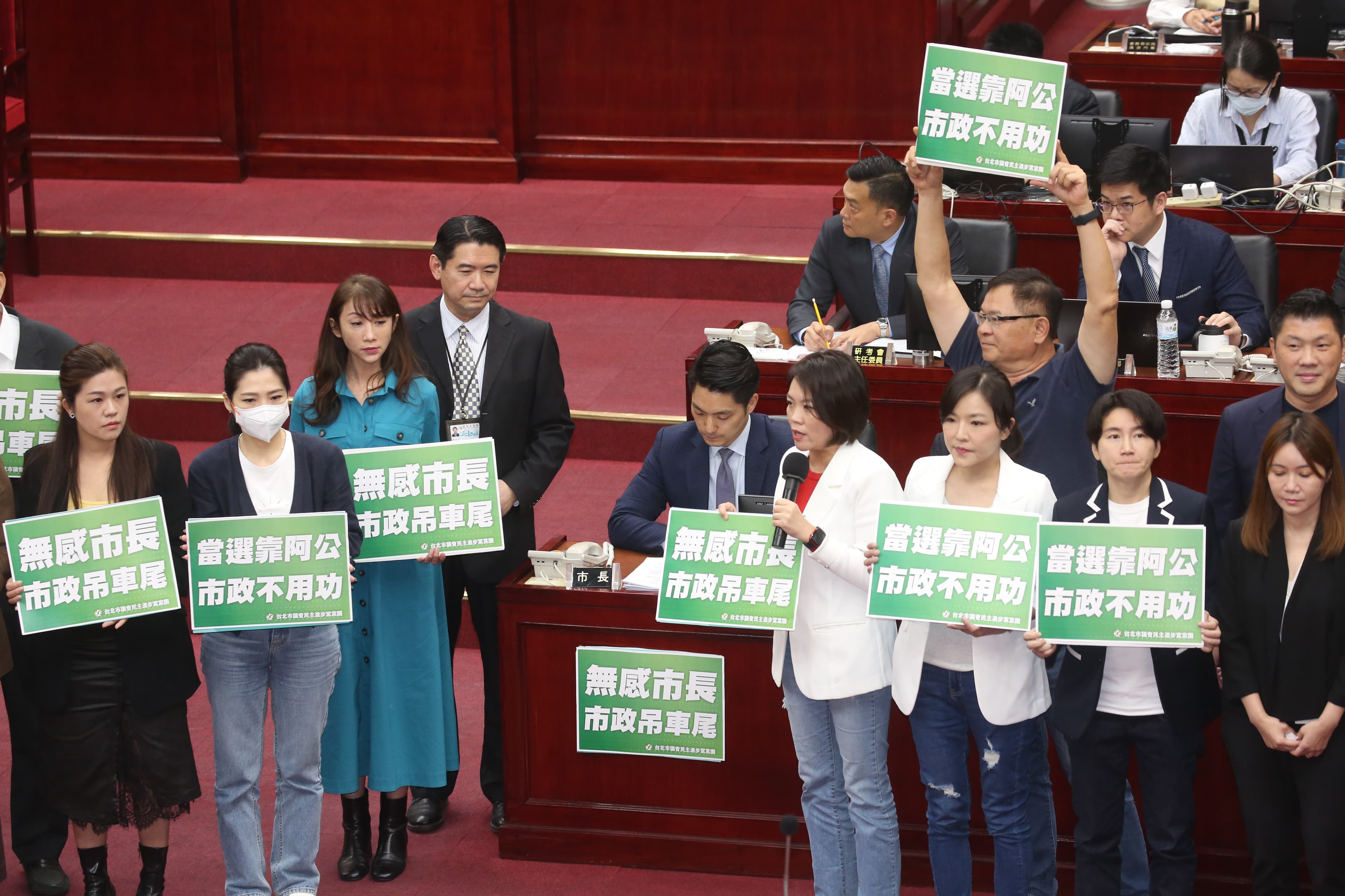 民進黨團在蔣萬安身旁舉牌,批其當選靠阿公、無感市長等。