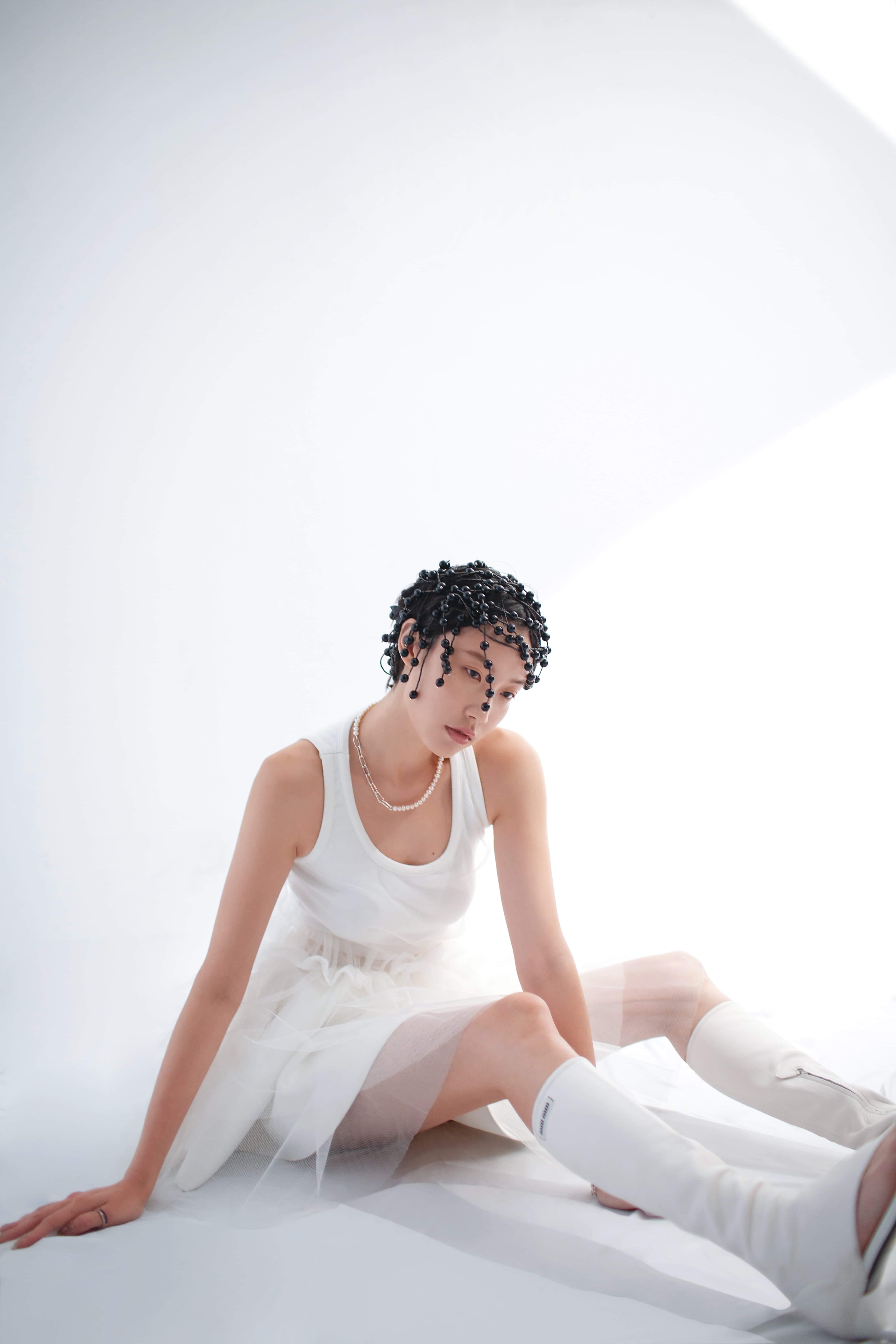 薄紗拼接洋裝NT$18,800 by MSGM；白色針織短裙NT$83,000 by LOEWE；彈性納帕軟皮夾趾長靴NT$70,000 by MIU MIU；黑色珠飾髮飾NT$176,900 by GUCCI；Pandora ME系列人工淡水養殖珍珠項鍊NT$9,980 by PANDORA；Pandora ME系列密鑲寶石配紅色琺瑯戒指NT$1,580 by PANDORA；Pandora ME系列密鑲寶石配藍色琺瑯戒指NT$2,480 by PANDORA。