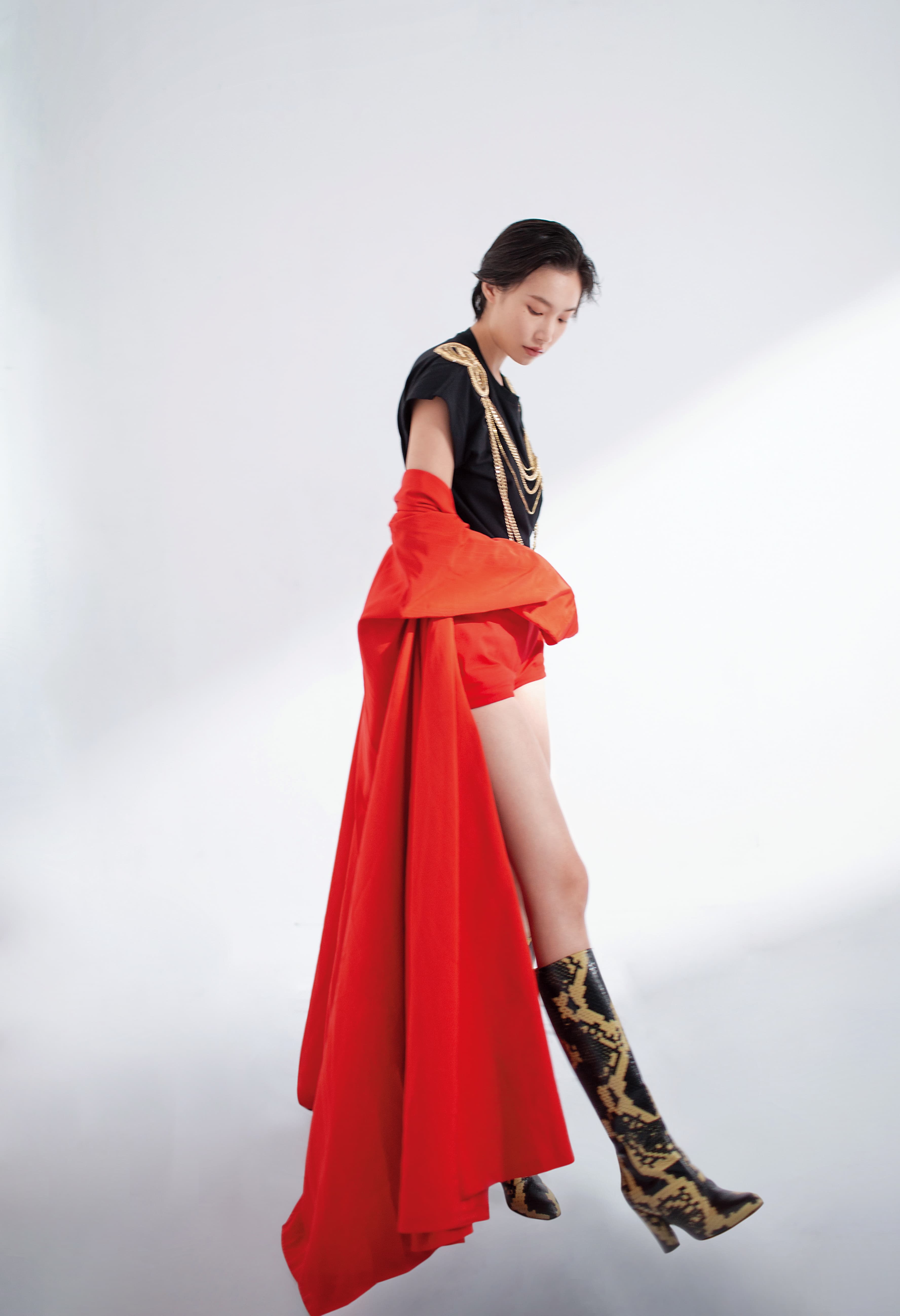 紅色長袖大衣NT$112,600 by GUCCI；刺繡短版T-Shirt NT$53,900 by BALMAIN；棉質短褲 未定價 by PRADA；蟒蛇紋中跟靴  價格店洽 by GUCCI。