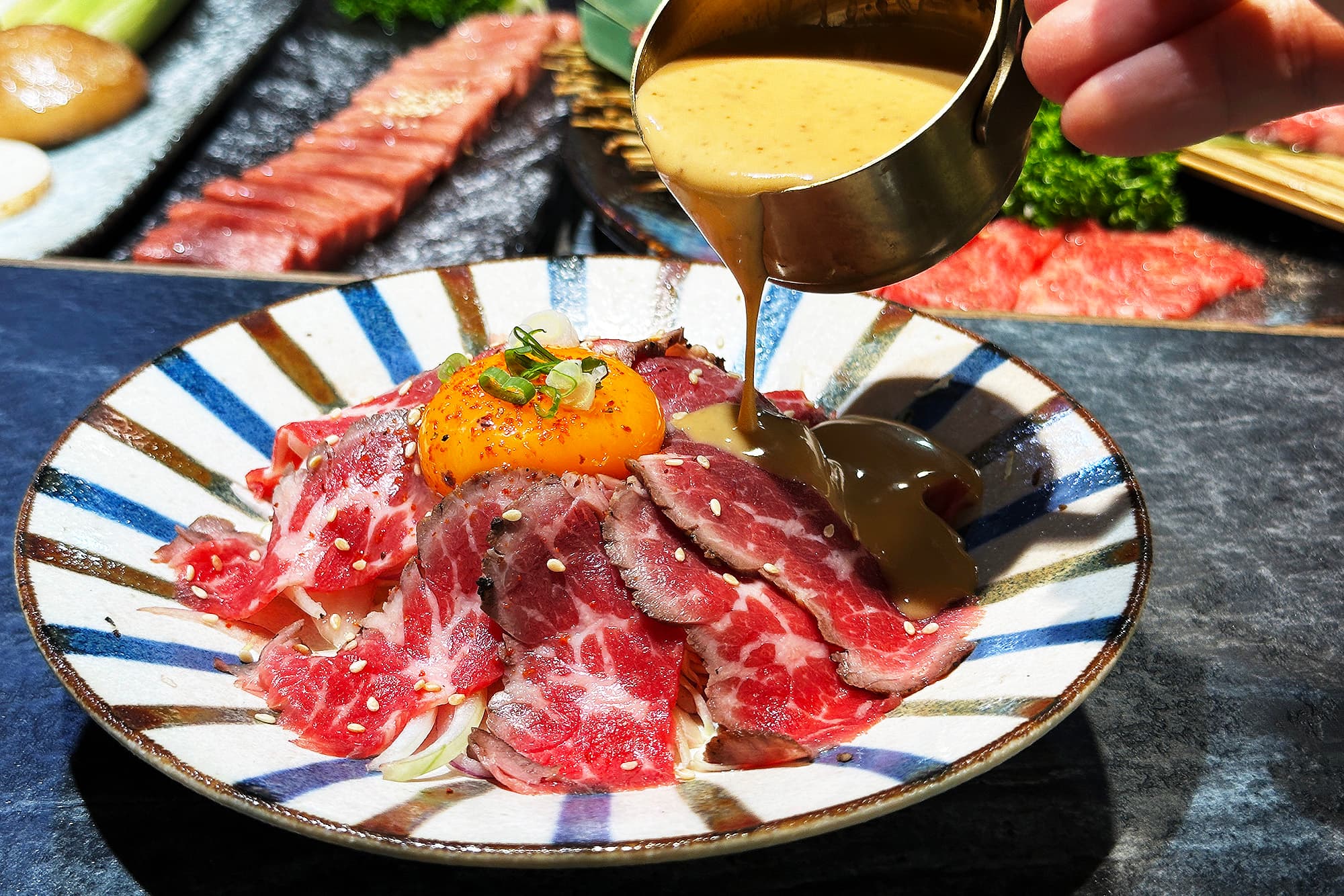在品嘗「日式辣胡麻生牛肉」時,可先將上方的生蛋黃戳開,再淋上微辣胡麻醬,蛋黃讓牛肉的口感瞬間變滑嫩,彷彿頂級生魚片般入口即化。(360元/份)