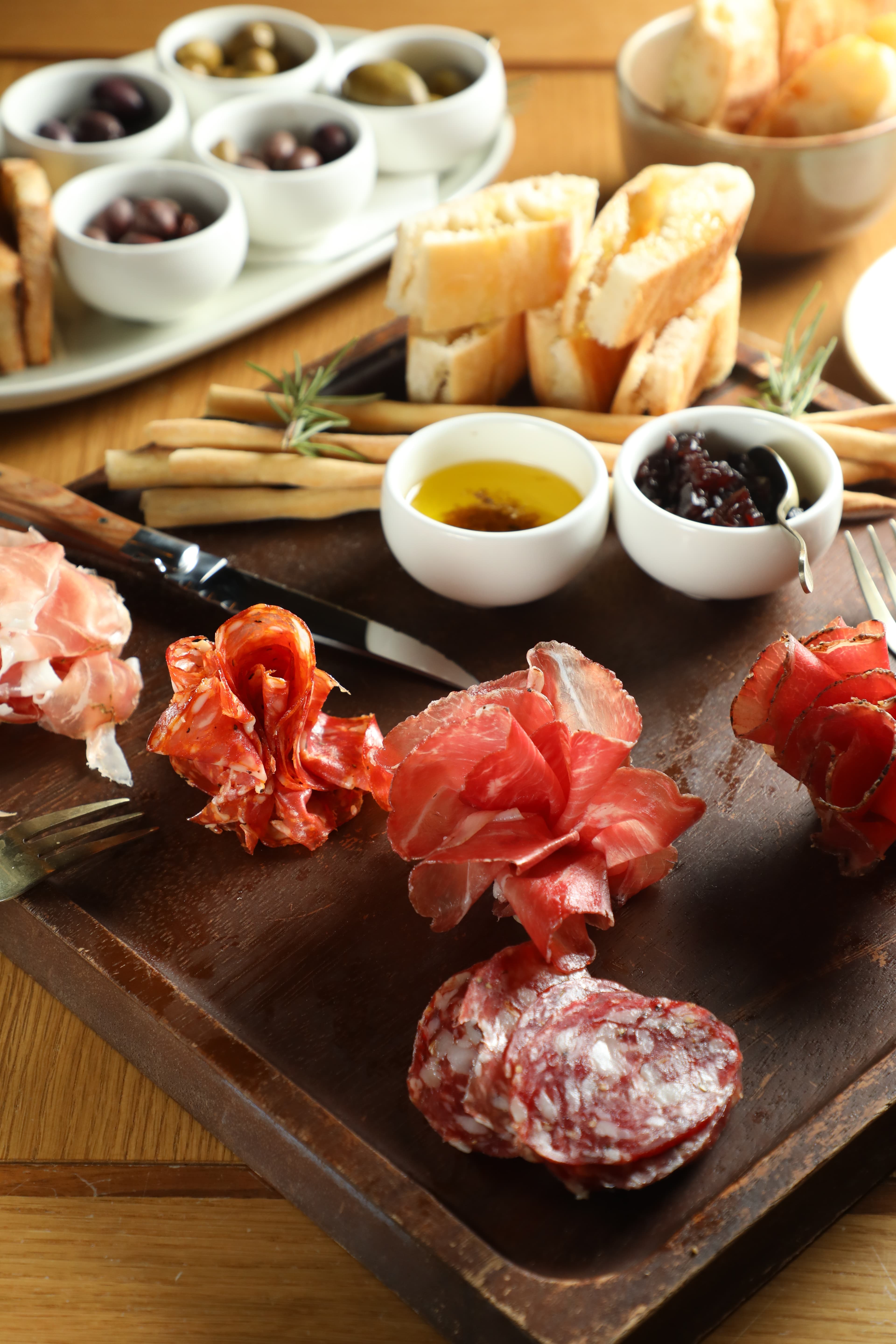 綜合熟肉盤「PUOPOLO ARTISAN SALUMI」(前,)鹹香美味,集滿5種橄欖的「PARAFIELD OLIVES」(後,)也很涮嘴。