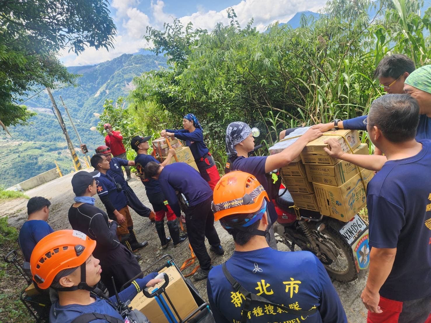 因道路通行受阻,搜救團隊只能透過徒手攀爬,靠近受困地點,以人力接龍搬進物資。(翻攝自新北消防發爾麵)