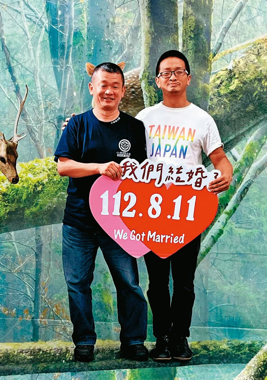 柴口征寬（左）與劉靈均（右）11日在北市大同戶政事務所登記完婚，開心地高舉「我們結婚了」標語。（劉靈均提供）