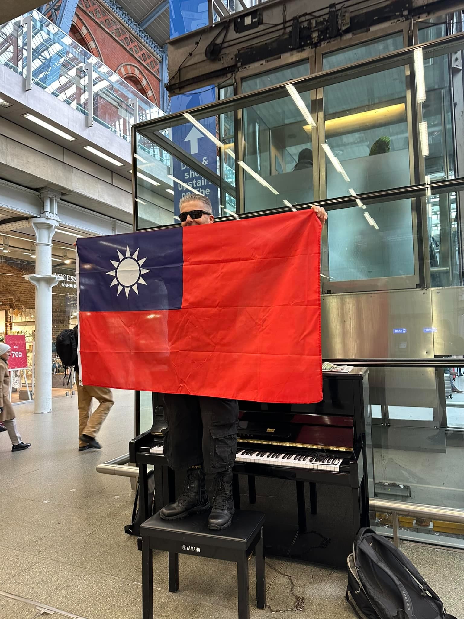 英國鋼琴家卡瓦納在倫敦聖潘克拉斯車站高舉中華民國國旗。(翻攝自Dr K Boogie Woogie臉書)