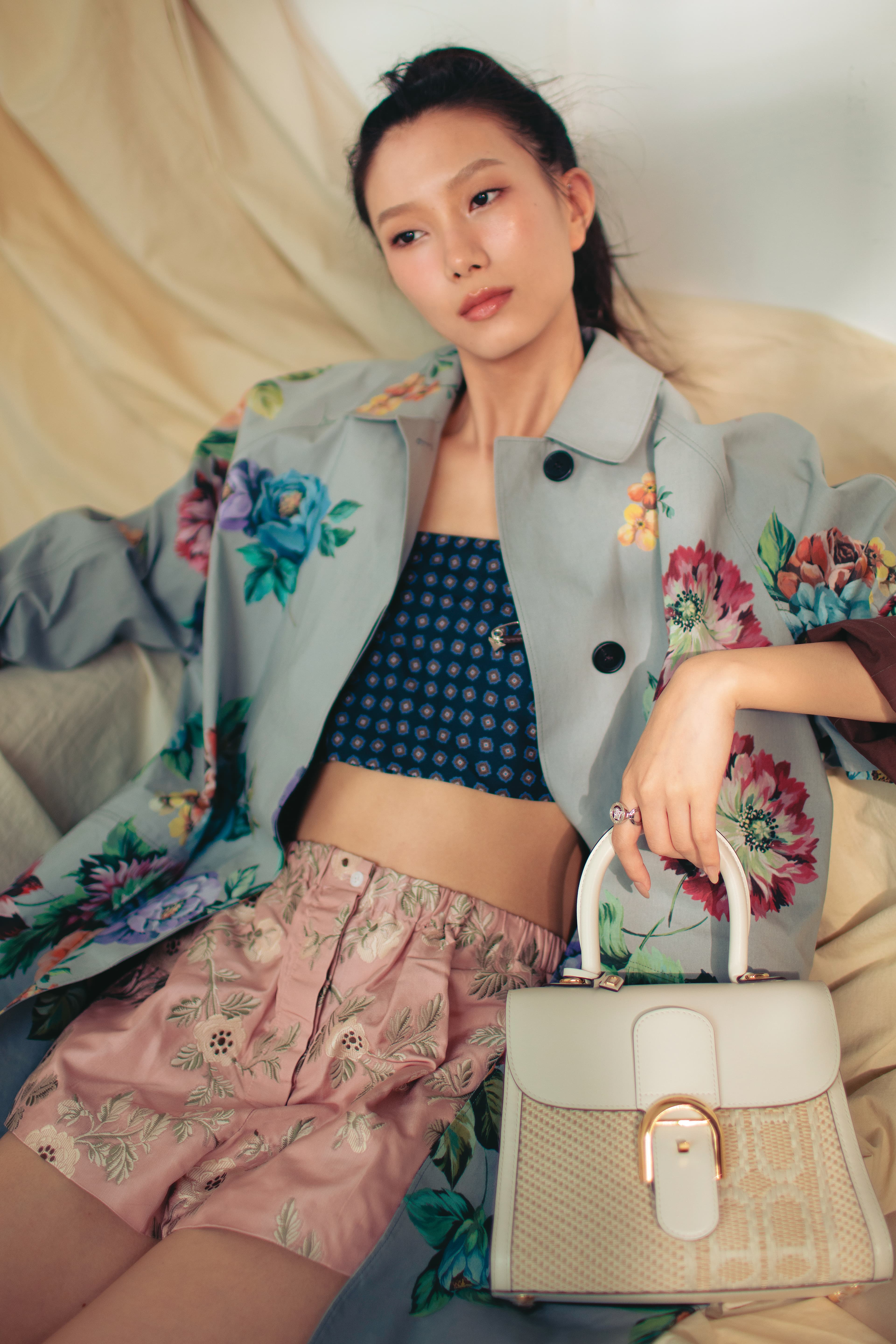 燕麥色與象牙白Brillant PM Versus Jacquard Illusion包款 NT$226,400 by DELVAUX／灰色花卉風衣 價格店洽 by PRADA／深藍色印花細肩帶上衣 價格店洽 by PRADA／粉色花卉短褲 價格店洽 by PRADA／Medusa '95水晶戒指 NT$12,000 by VERSACE
