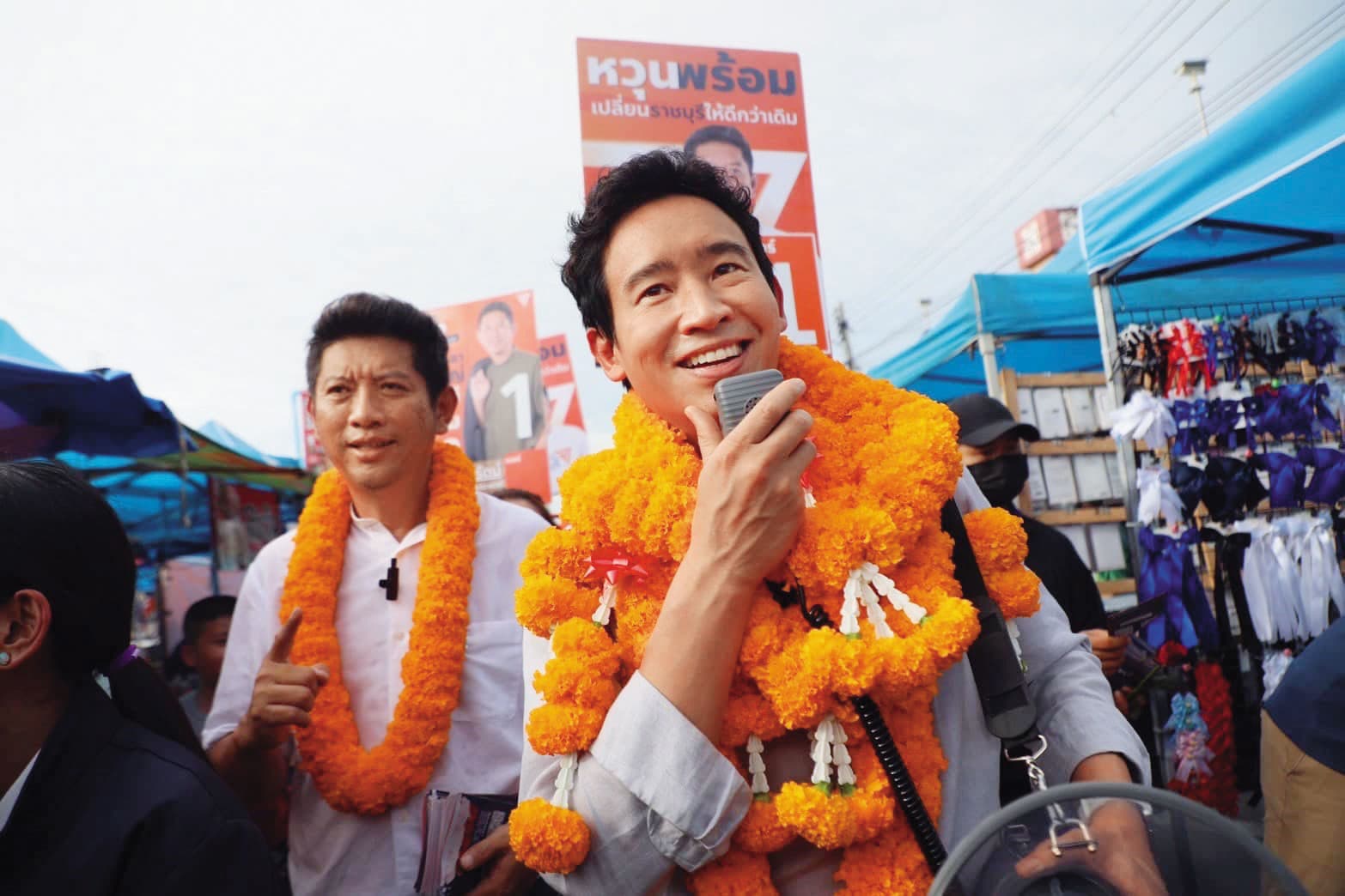 2月8日是泰國大選日。皮塔(右)是人民黨的最佳助選員,身上掛滿民眾給他的萬壽菊花環,掛得越多,代表人氣越高。(翻攝自皮塔臉書)