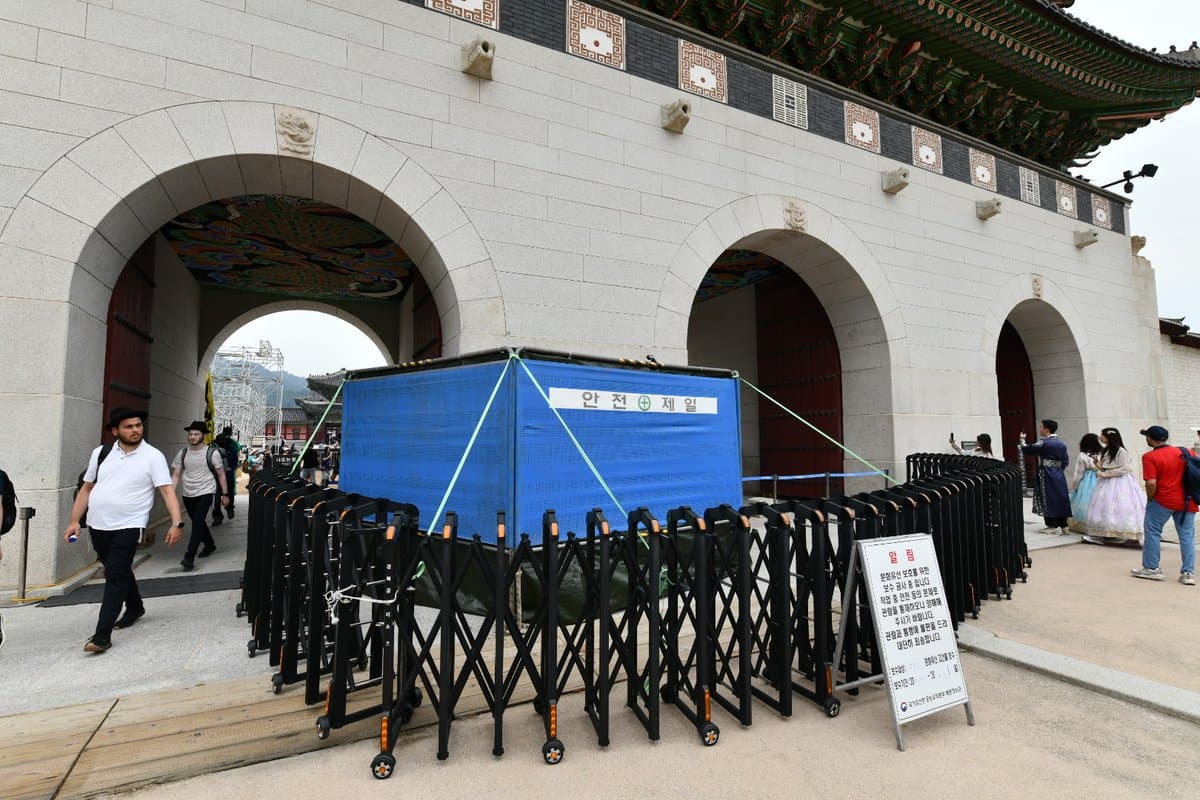 南韓國家遺產廳相關人員迅速清除掉景福宮光化門石牆上的塗鴉。(翻攝自臉書@국가유산청 )