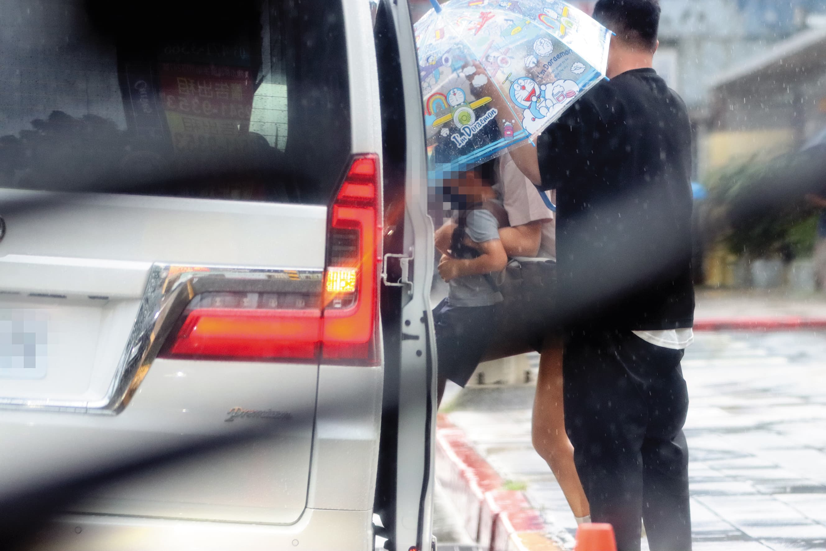 8/15 16:22 安以軒(中)必須手與膝蓋並用,才能把五歲兒子弄上車,此時還下著大雨,感覺更狼狽。