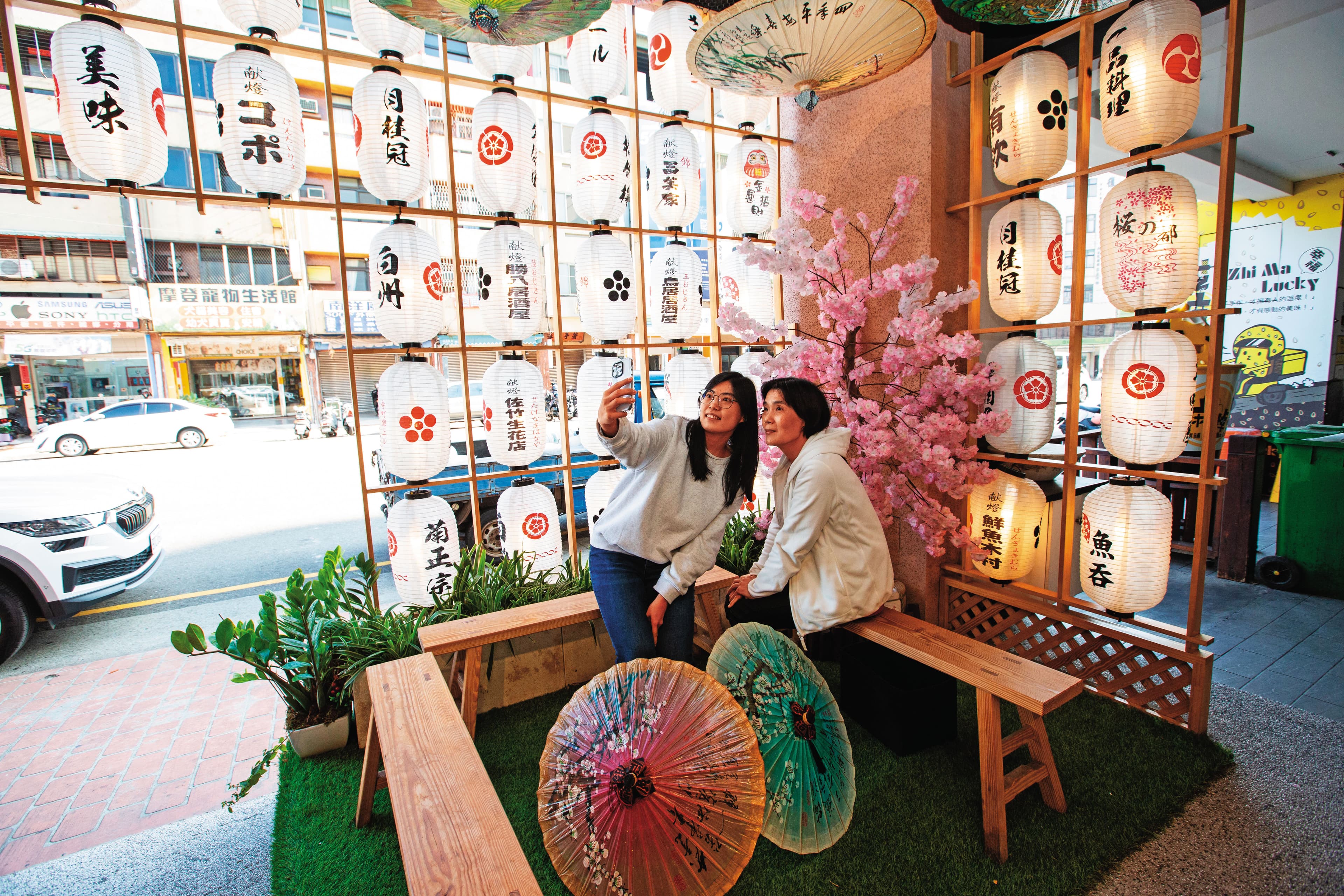 魚吞壽司店外候客區設計有美美的日式燈籠、美濃紙傘網美牆,吸引顧客拍照打卡。