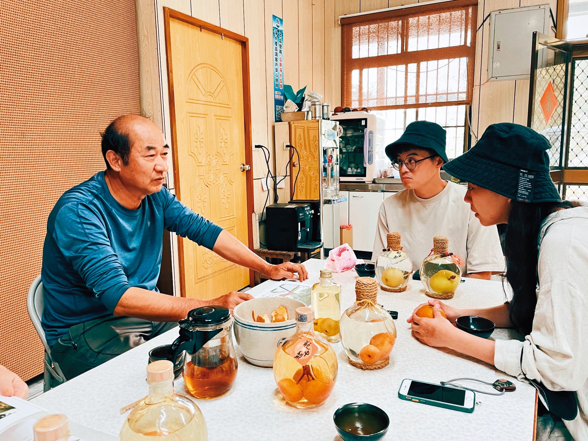 何安妘(右一)以台中東榮農場老闆蘇光明(左一)製作「瓶中梨」的甘苦,轉化成帶有奇幻風格的作品〈酒是機率—永不分離的機率〉。右二為繪製〈酒是遺憾—黑米糰子與酒〉的漫畫家錢君銜。(聚場文化提供)