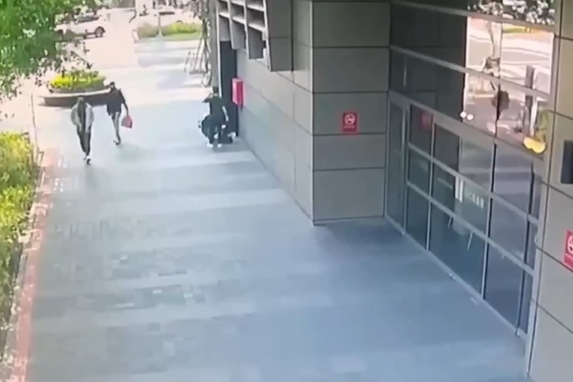 趙姓及許姓男子躲在柱子後，確認交易正在進行，隨即持刀上前搶錢。（翻攝畫面）