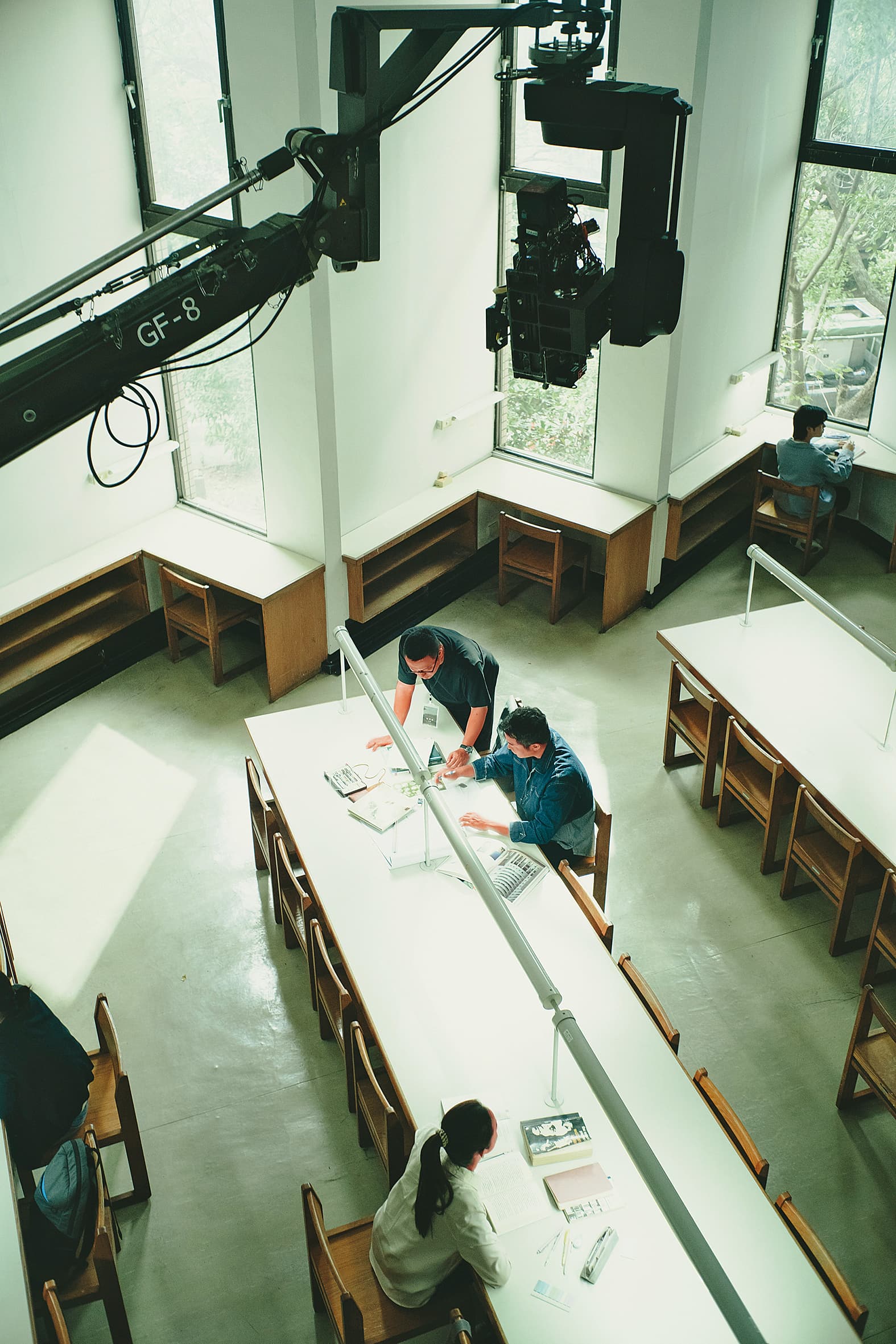 電影第一場戲在政大圖書館拍攝,導演沈可尚(上)與演員張孝全(中)、林依晨(下)溝通討論。(風起娛樂提供)