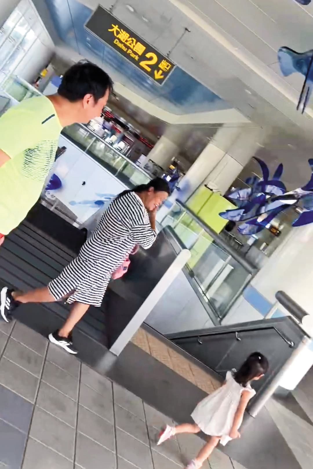 九孔（左）帶著兩歲女（右）到大湖公園玩耍結束後，與移工（中）一起進入捷運站。（讀者提供）