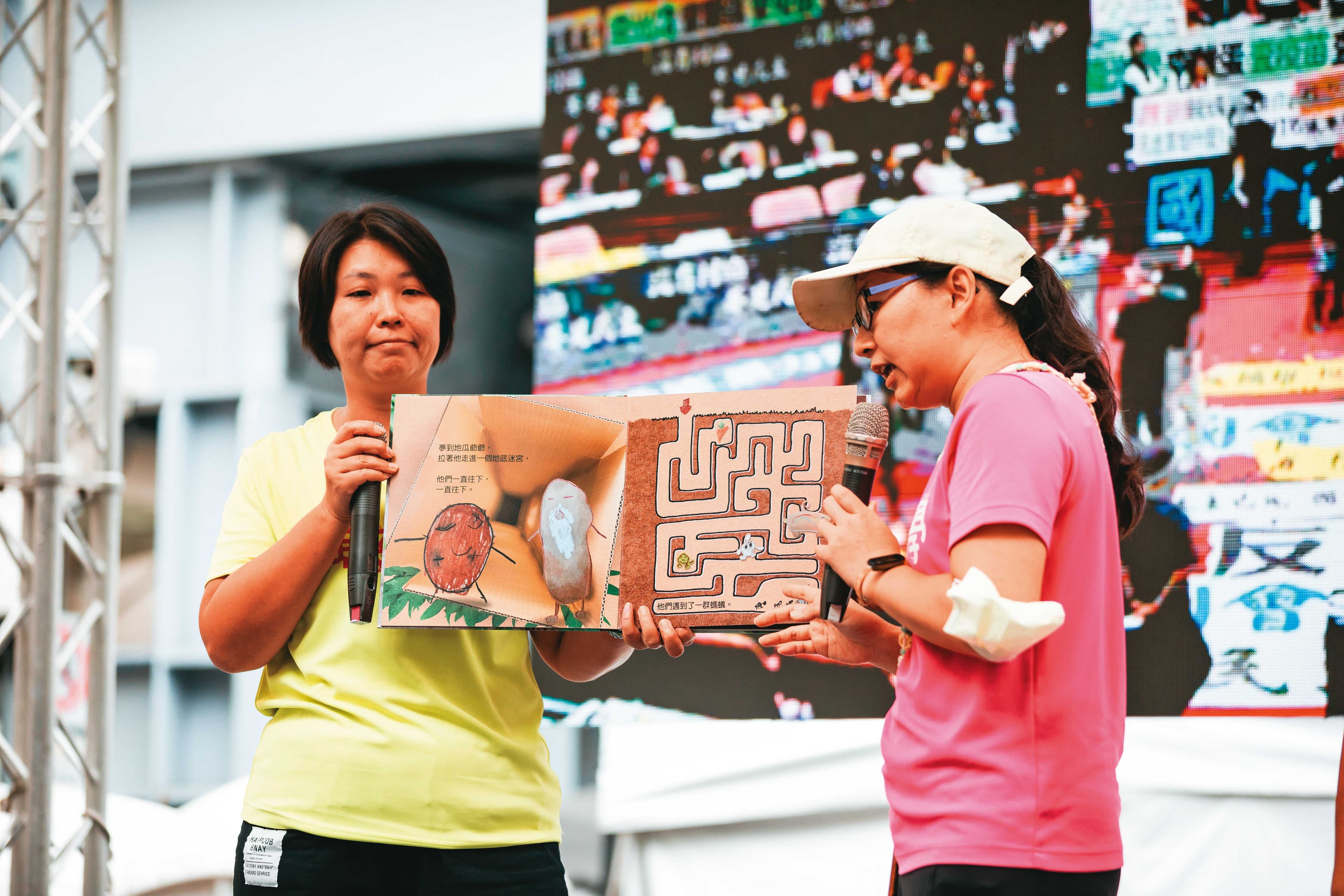 台灣親子共學教育促進會在舞台上朗讀繪本,手上拿的是親子共同以「竹科三期開發案」為本創作、談程序正義議題的《地瓜打嗝了》。