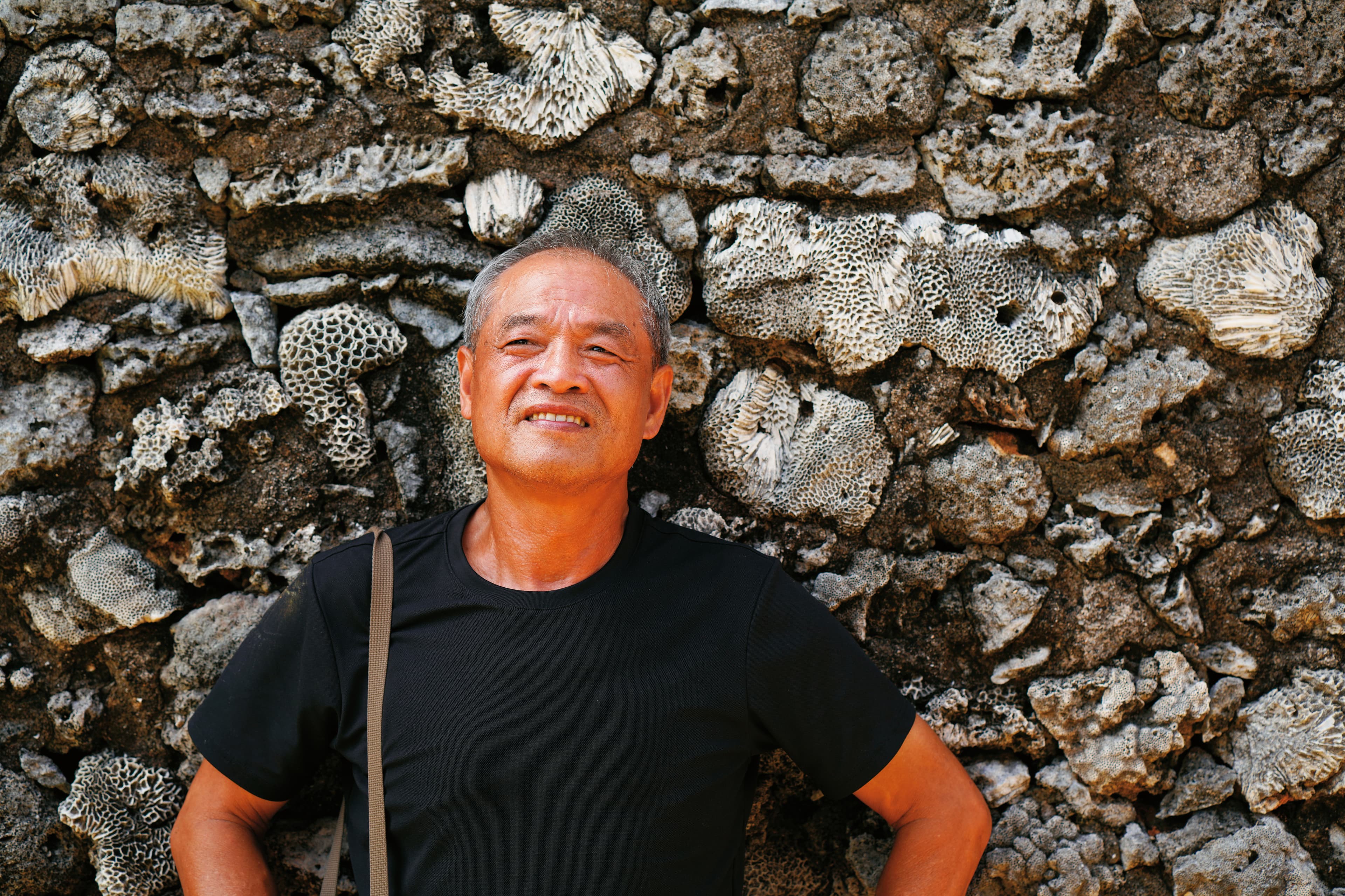 謝三泰在澎湖傳統建築的咾咕石牆前。澎湖曾是他一心逃離的地方,卻也是漂泊異鄉四十多年後想回返的原鄉。