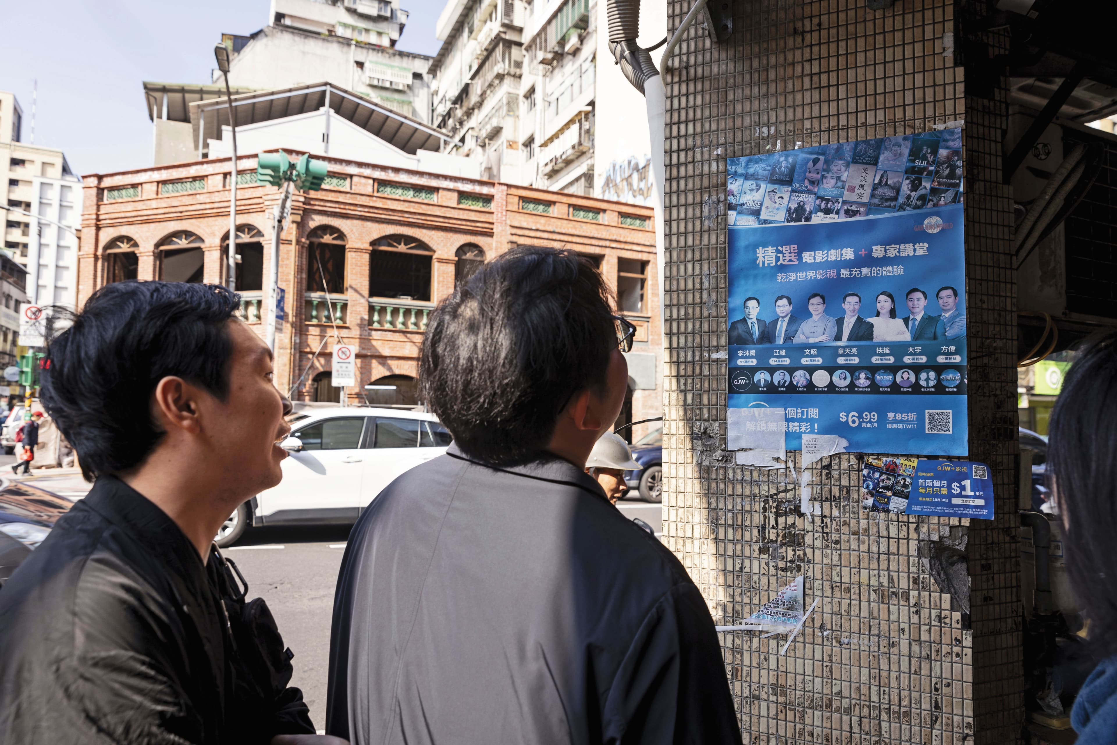 李穎(右)、多倫多方臉(左)訪台期間在街頭走動,無意看見牆面張貼斑駁的中國海外反共人士活動海報,2人駐足觀看許久。