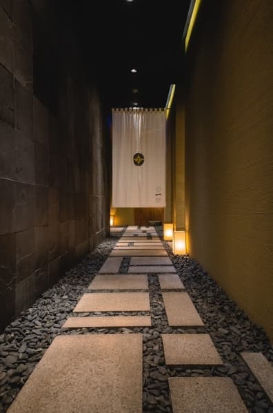 走過一段石板路,穿過印有押野家徽的暖簾,才正式進入用餐空間。(赫士盟提供)