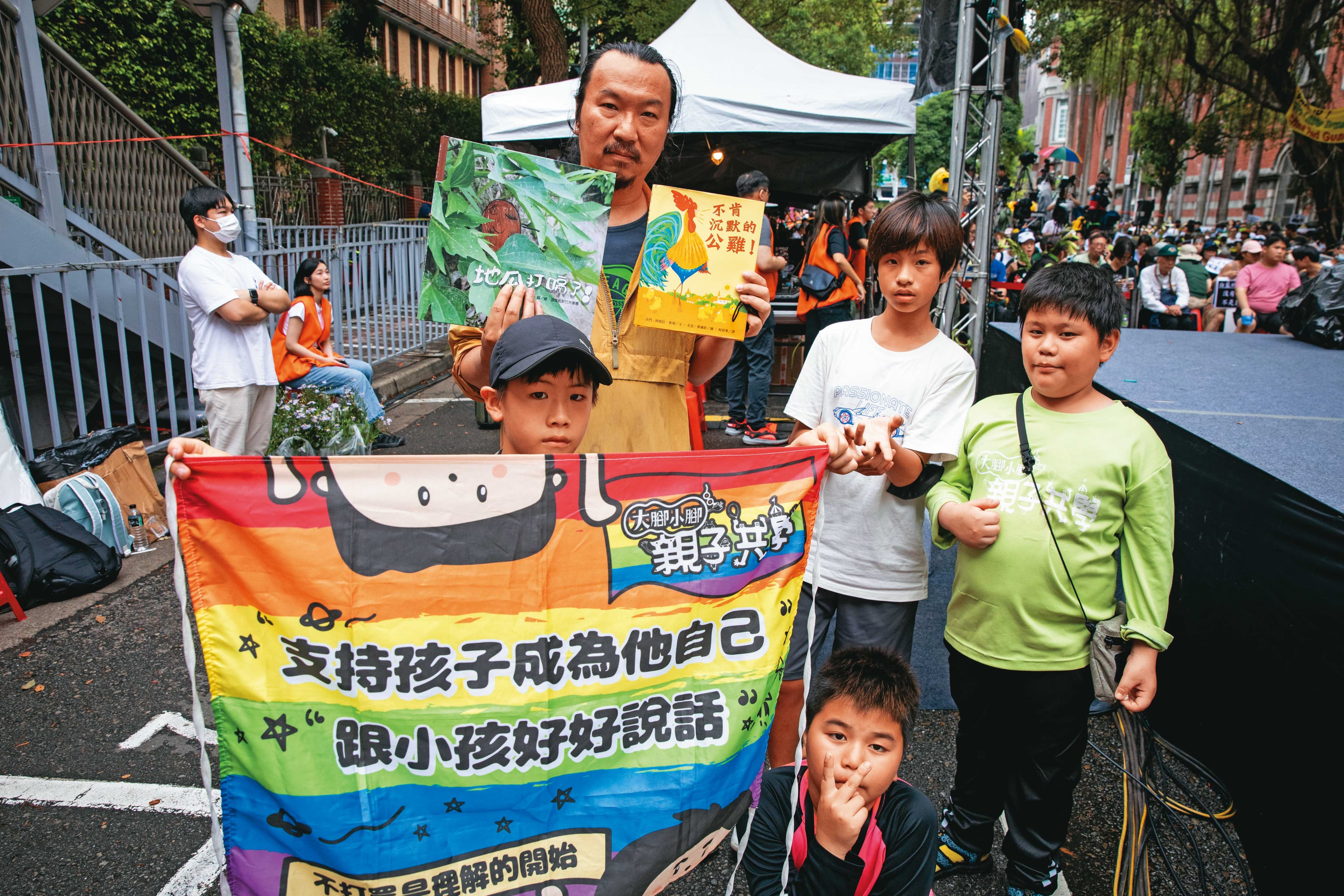 林壯穎和一群共學團的孩子,在青島東路主舞台旁合照,手裡拿的是剛在台上朗讀過的繪本。