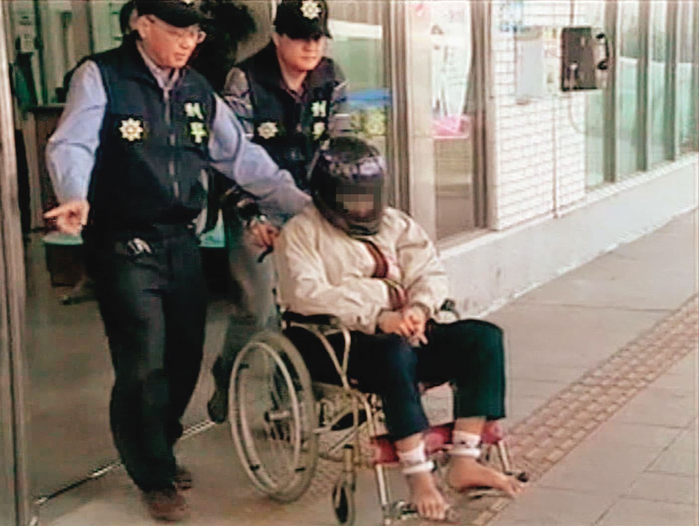 黃姓凶手(坐者)被警方借提時,假裝癲癇、行動不便,最後遭戳破謊言。(東森新聞提供)