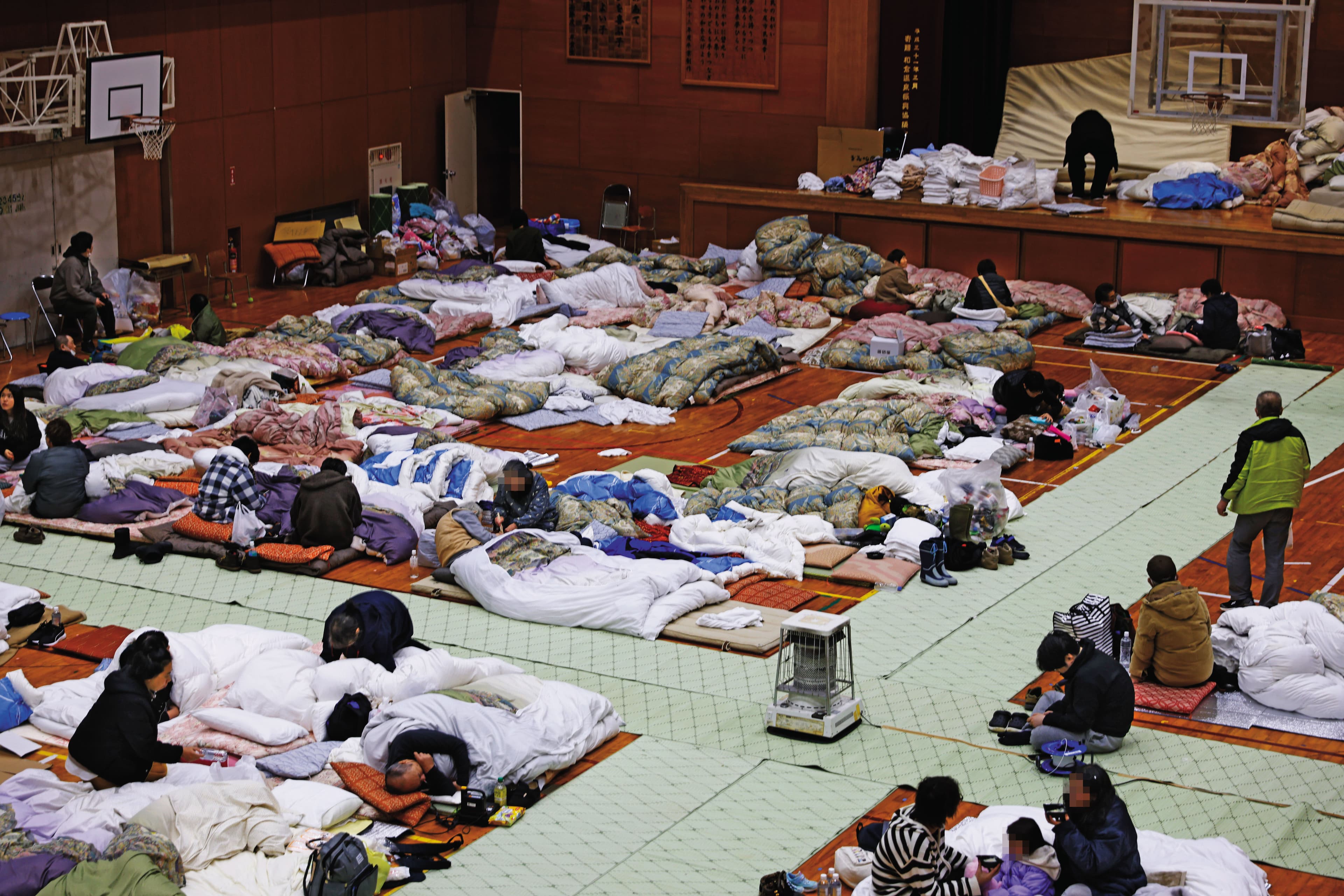 和倉小學臨時避難所收容1,400多名災民，他們扶老攜幼，裹著棉被取暖。