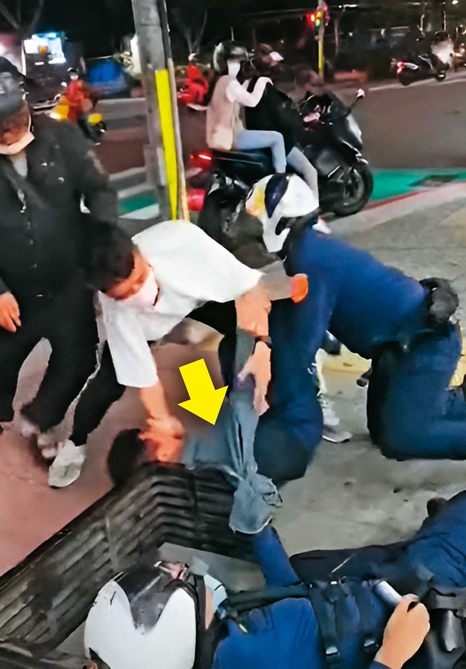 黃先生(箭頭處)被員警推倒在人行道上,一旁的民眾也上前協助員警逮人。(翻攝畫面)